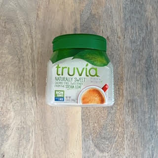 Jar of Truvia spoonable sweetener laying on wood table surface