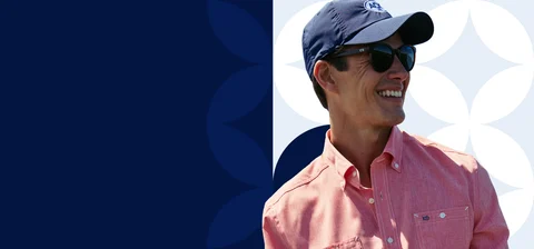 Man in pink shirt and blue hat smiling