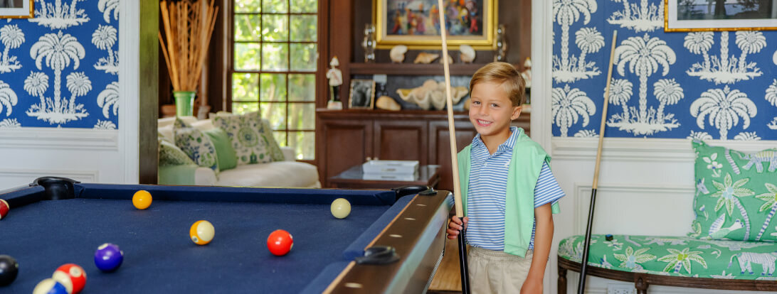 Young boy smiling next to pool table