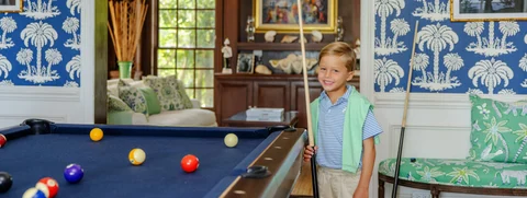 Young boy smiling next to pool table