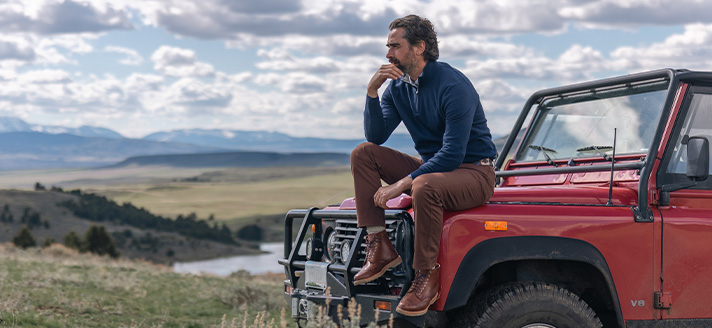 Man sitting on hood of red jeep