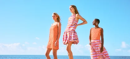 Three women standing on rocks in front of ocean