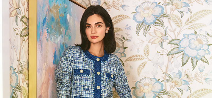 Women standing in front of floral wallpapered wall