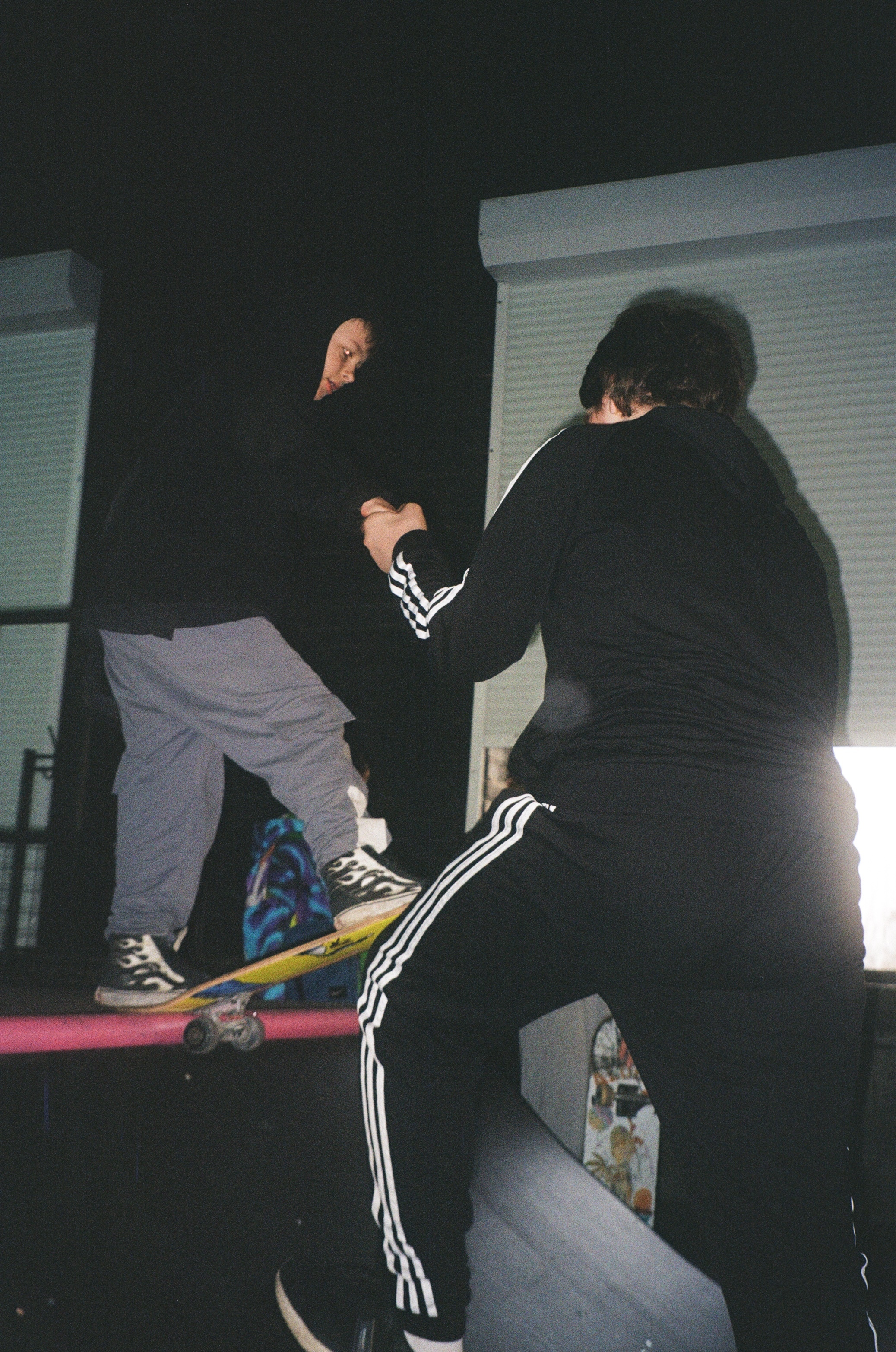 Two people in black clothing engaged in a physical altercation at night.