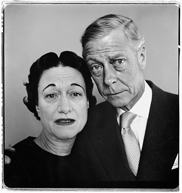 Black and white portrait of elderly couple, woman with dark curled hair and dark lipstick on left, man with light combed hair in suit on right.