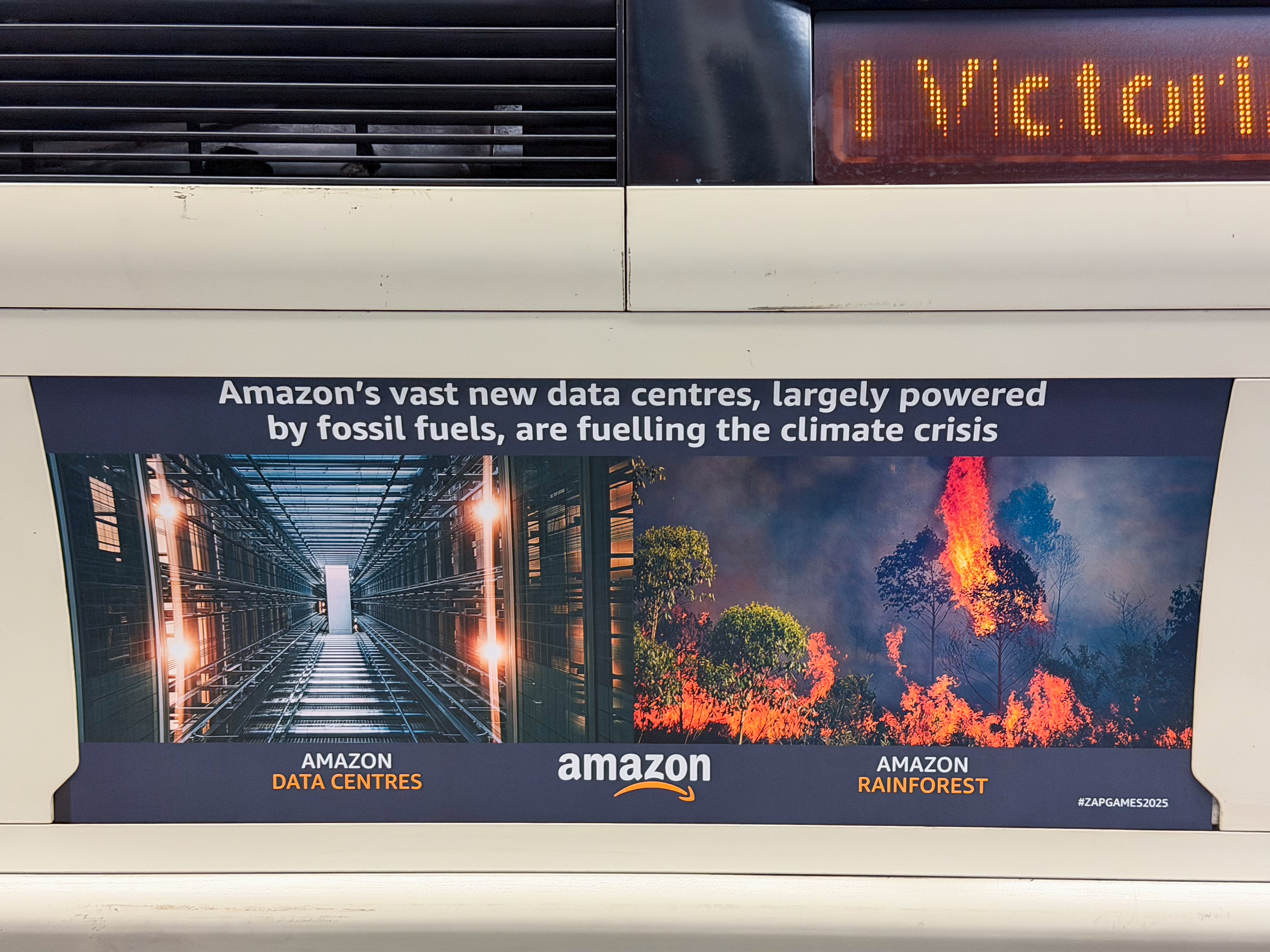 Advertisement poster on train showing Amazon data centre on left, burning rainforest on right, with climate crisis headline text.