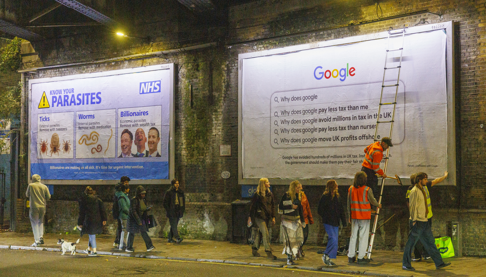 Railway station platform with large NHS parasites warning poster and Google search advertisement on brick wall. People waiting below.