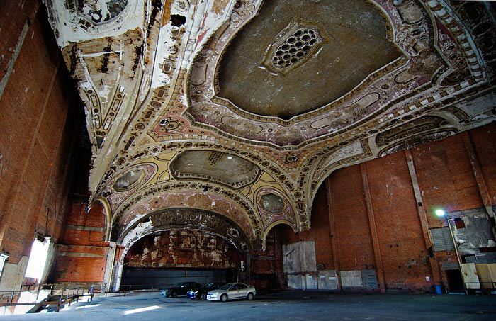 Ornate, decorative ceiling with intricate arches, patterns, and a central dome in an abandoned, dilapidated interior space.