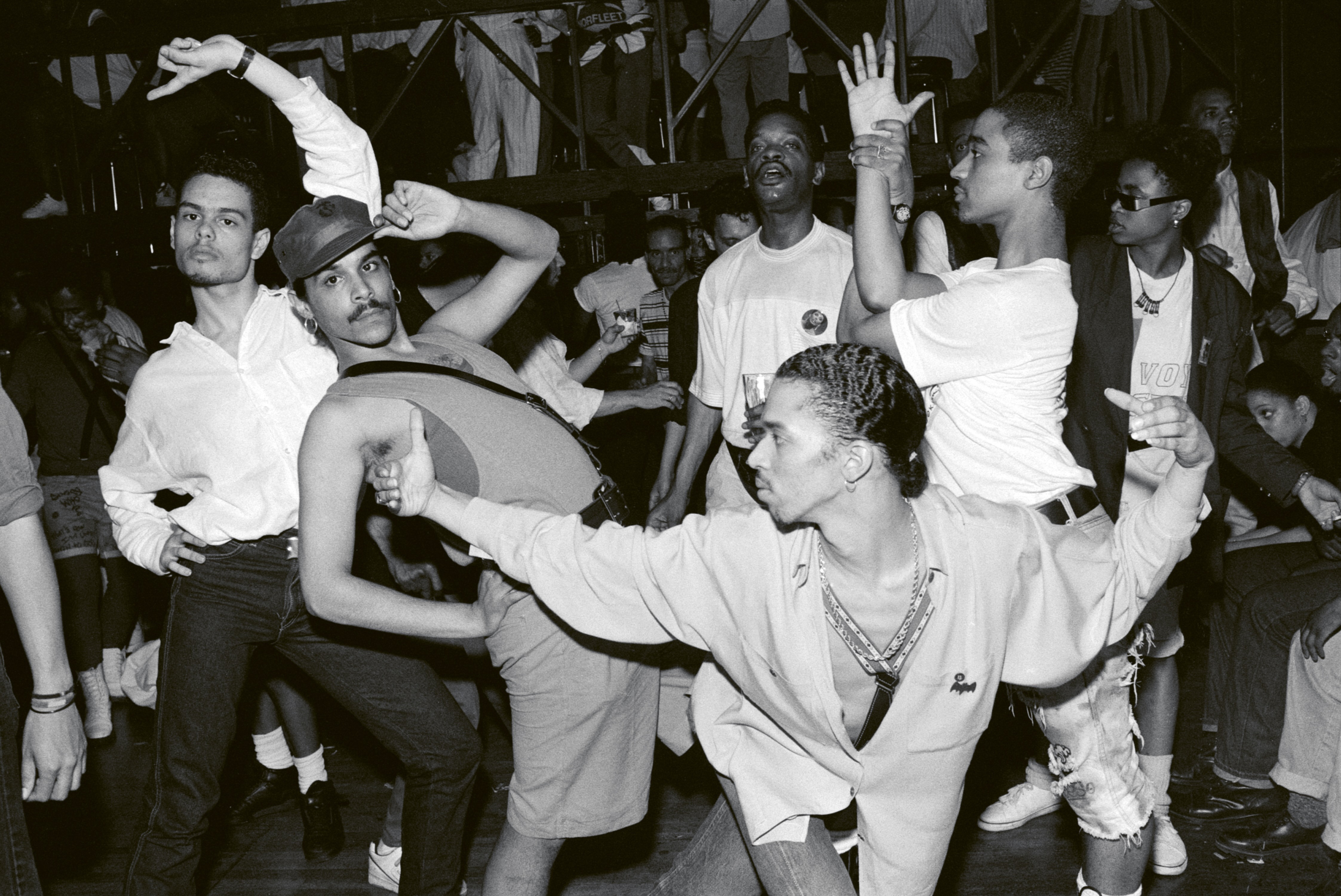 A group of people dancing at a lively party, some with their arms raised in the air.