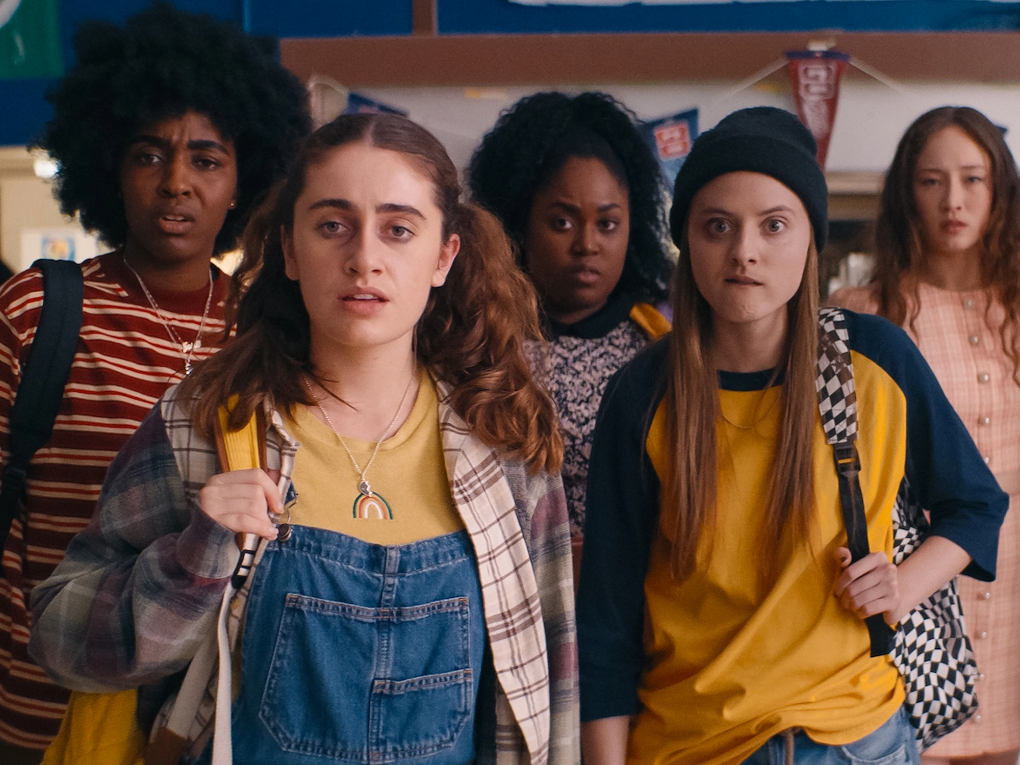 Group of diverse teenagers in casual clothing, standing together against a colourful background.