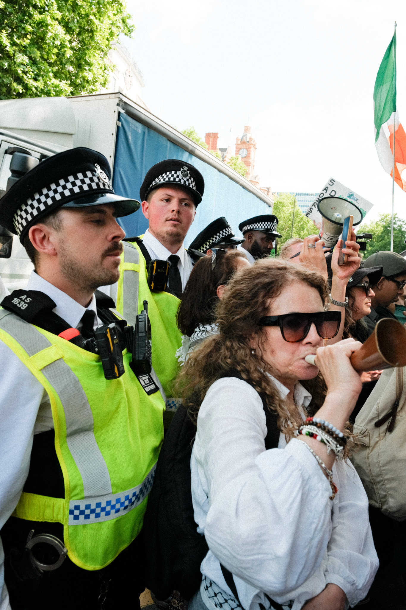 Police officers in hi-vis jackets with protesters in front of them, some holding banners and signs.