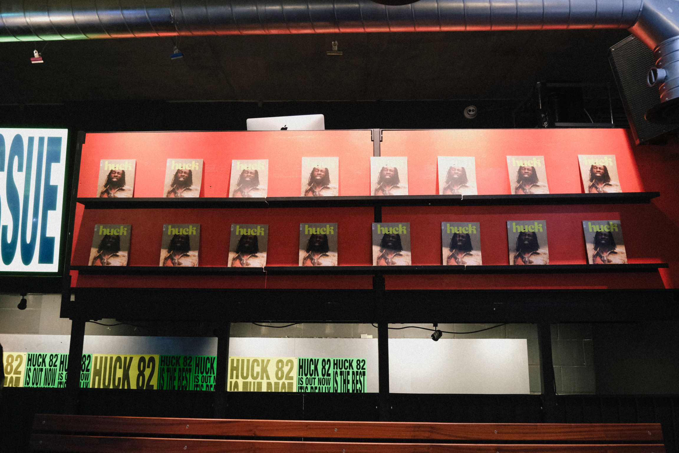Display case with two shelves of comic books in protective sleeves, orange and dark red backgrounds, green price labels below.