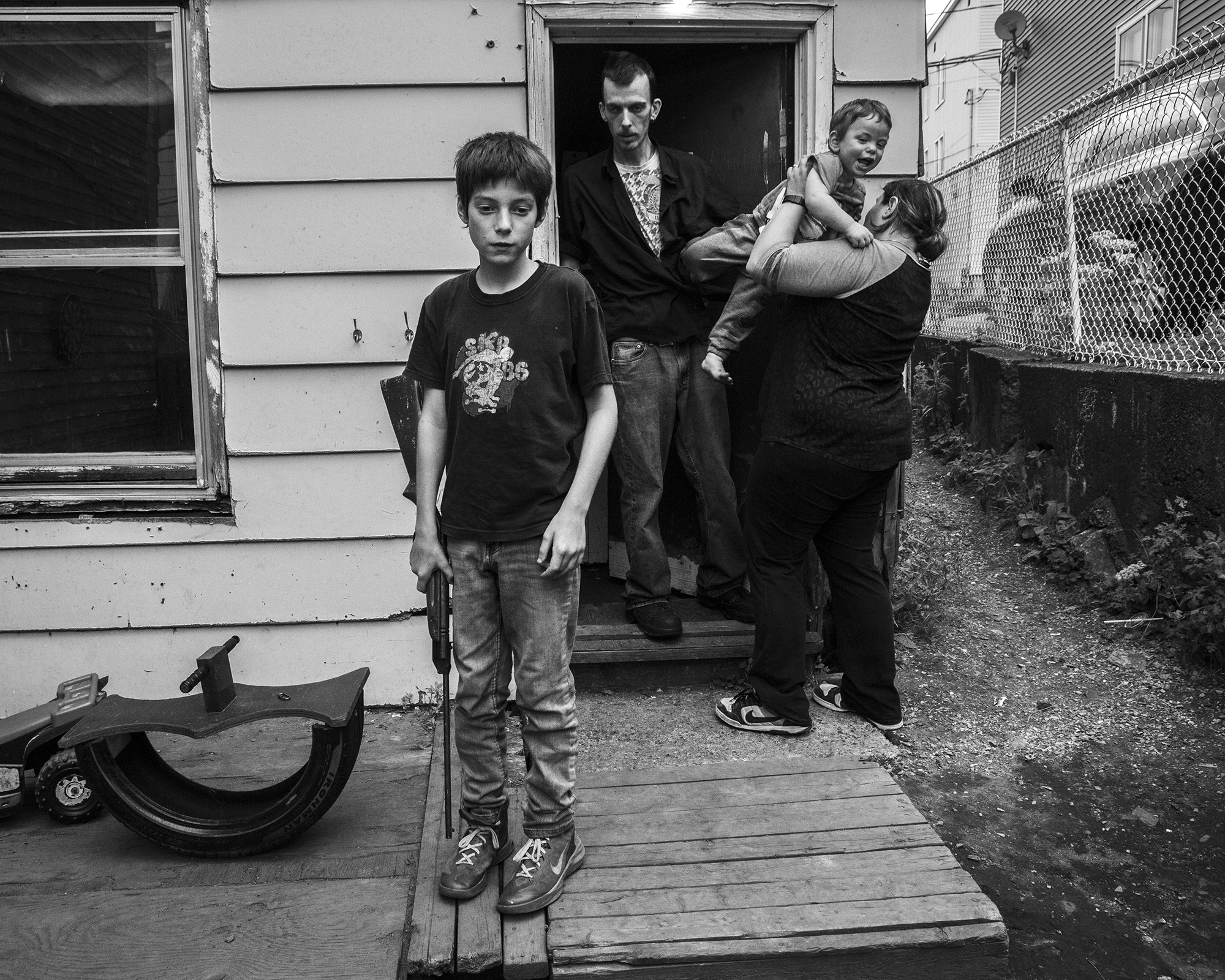 Two adults and two children standing on a wooden porch, black and white photograph.