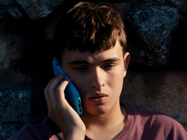 A young man with a troubled expression on his face, holding a mobile phone to his ear.
