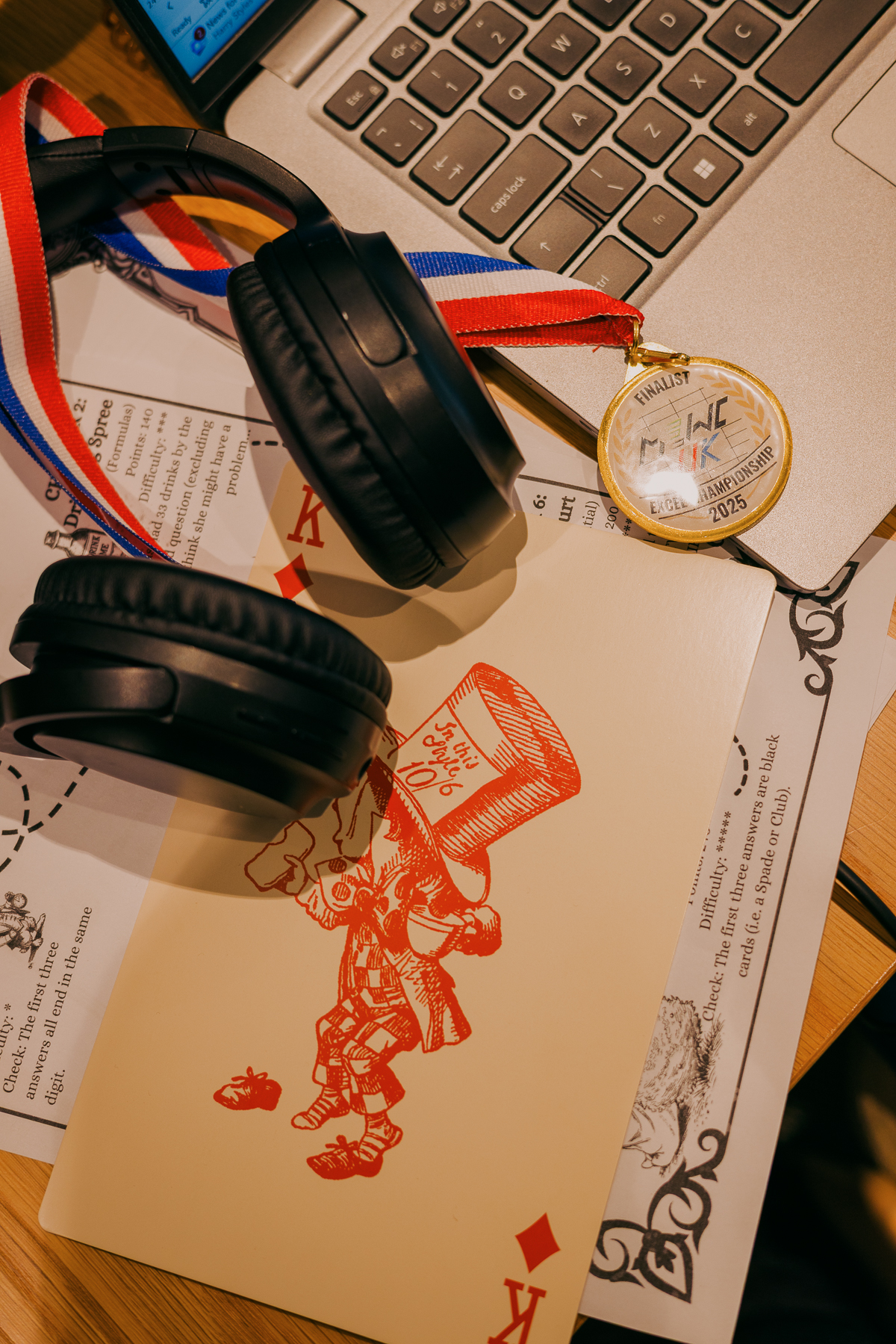 Black headphones, gold medal on red-white-blue ribbon, and red-stamped papers scattered on laptop keyboard.