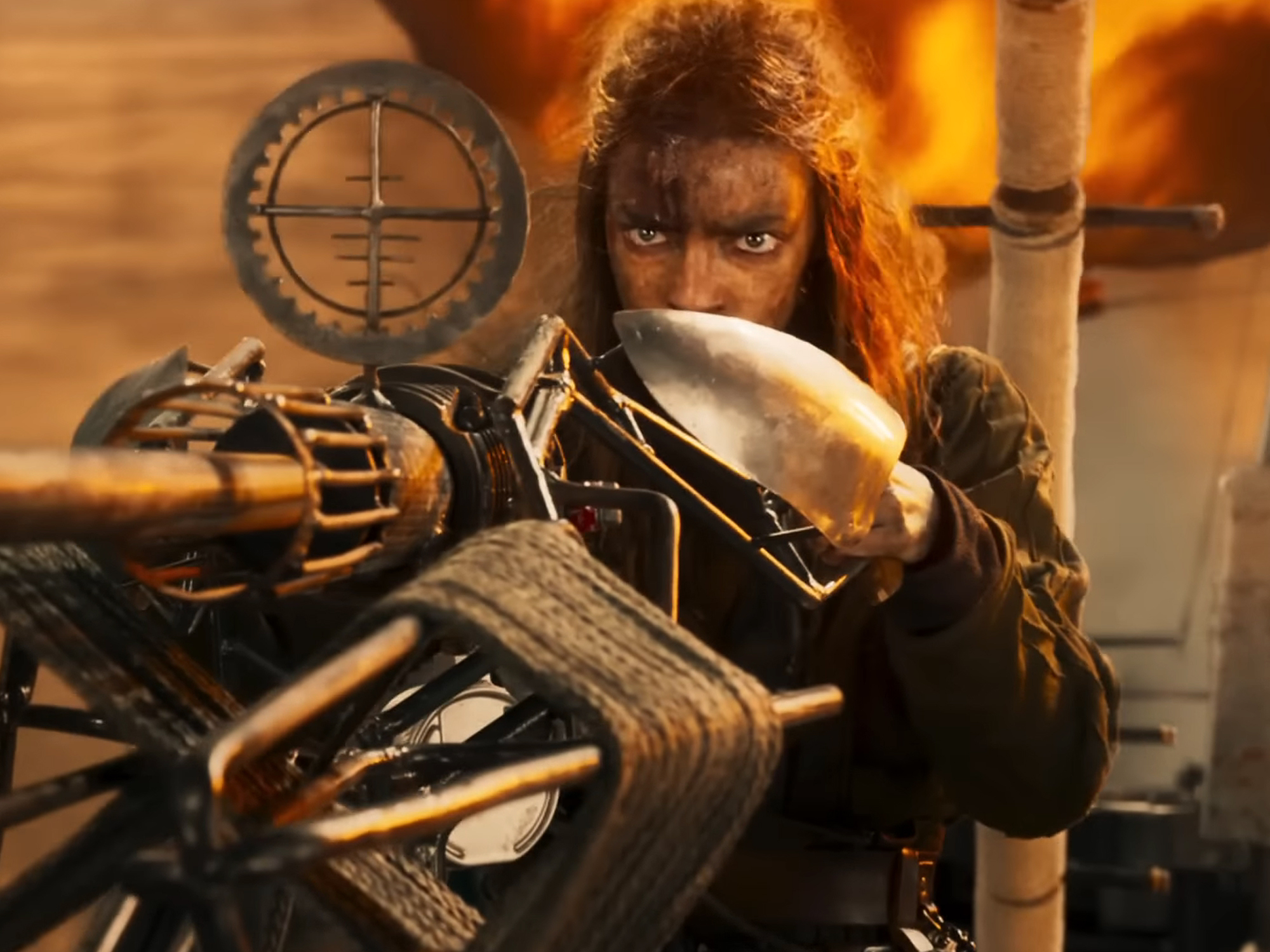 Close-up of a heavily armed and armoured person aiming a large weapon in a dark, industrial setting.