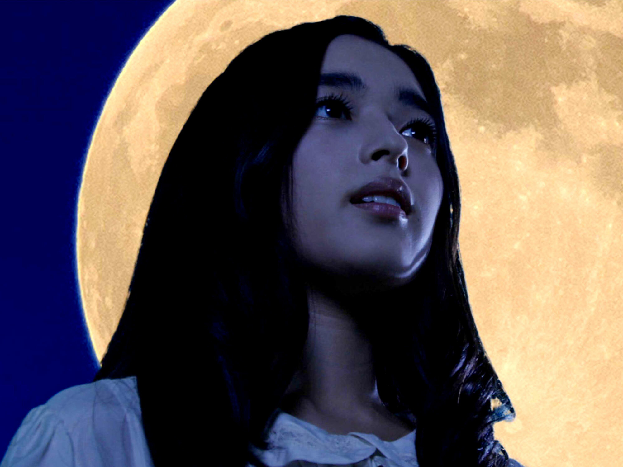 Woman's face set against a full moon, framed by dark hair.