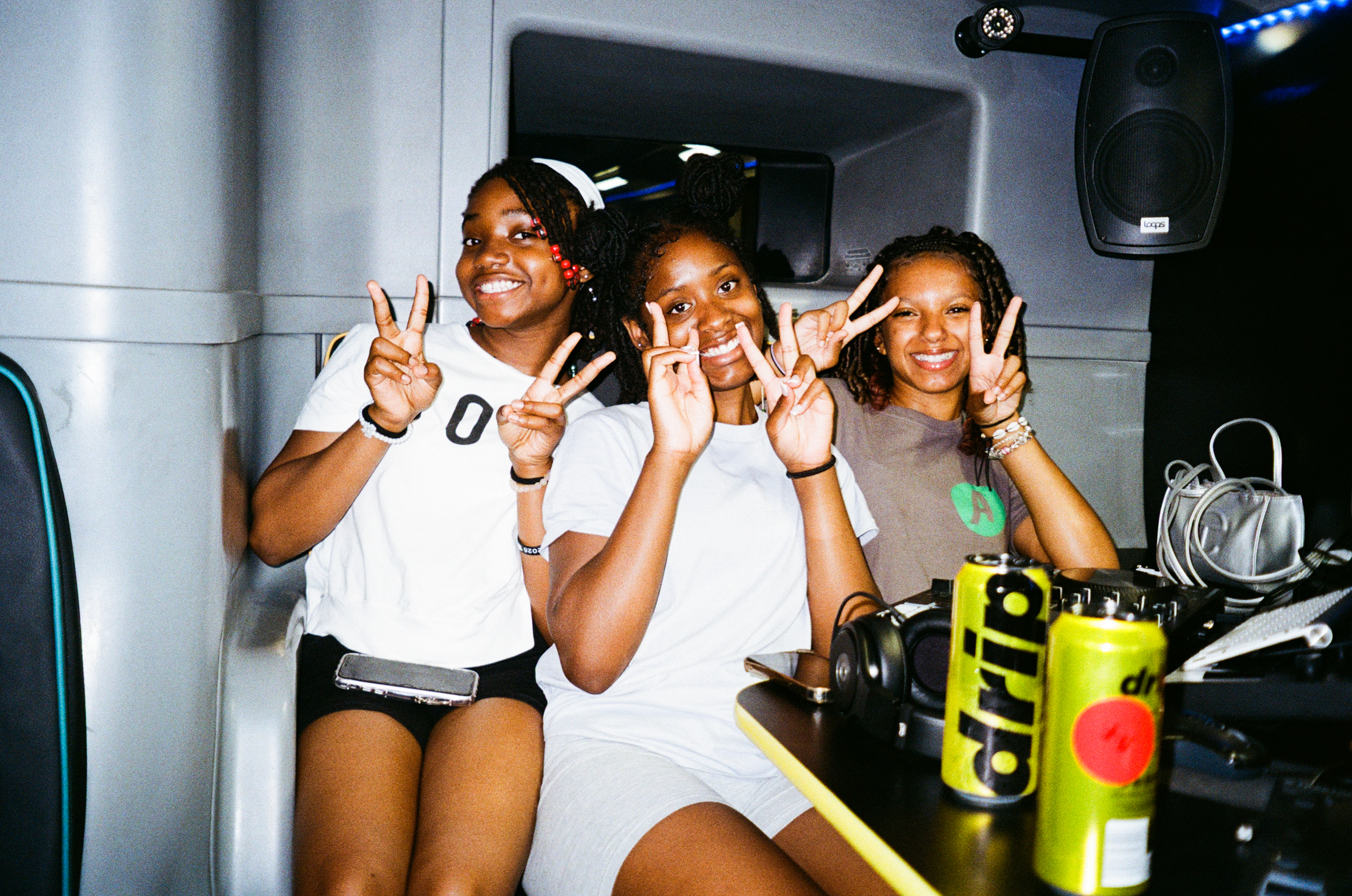 Three women making peace signs with their hands inside what appears to be a vehicle or recreational vehicle interior.