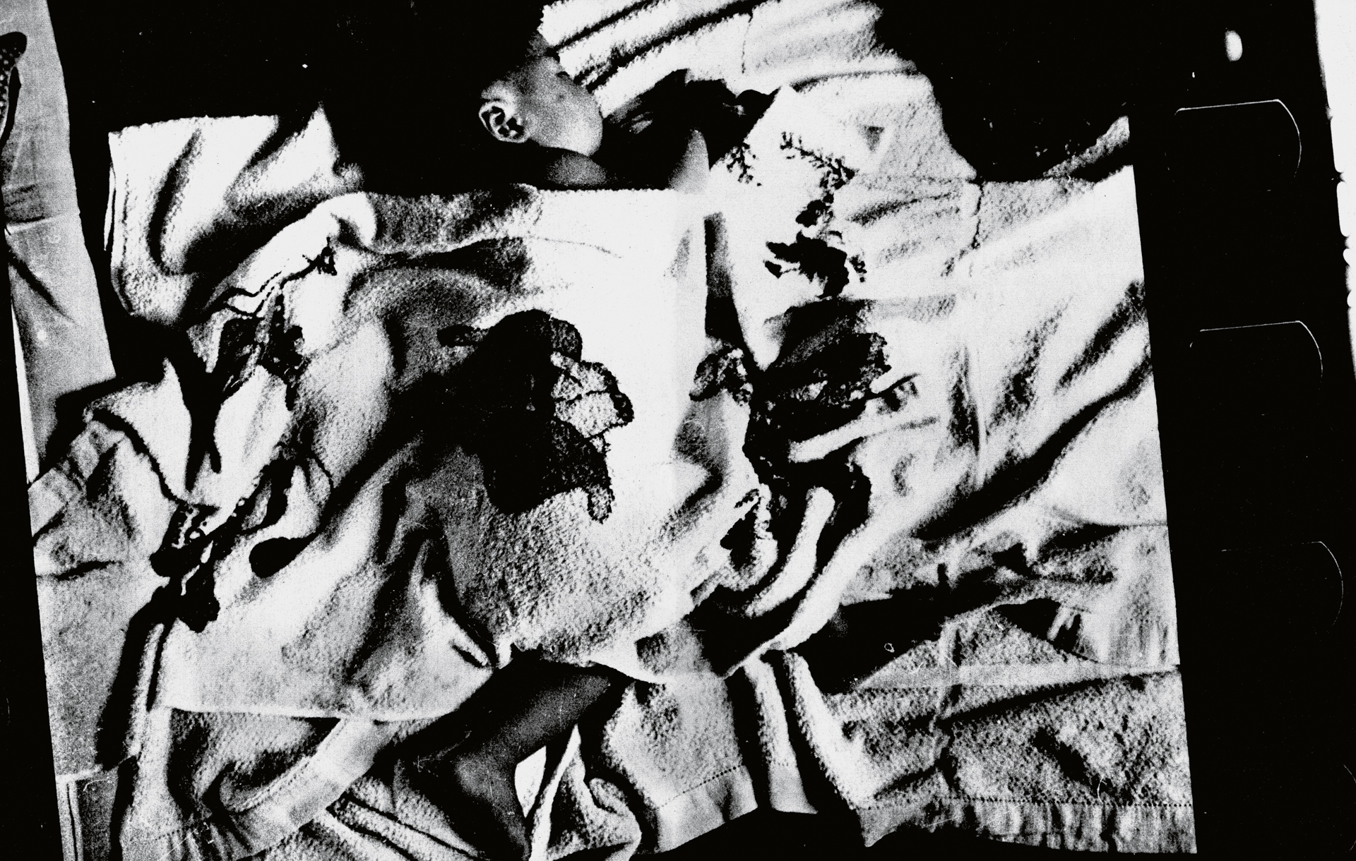 Black and white high-contrast image with abstract shapes, dark silhouettes, and fragmented geometric forms creating a collage-like composition.