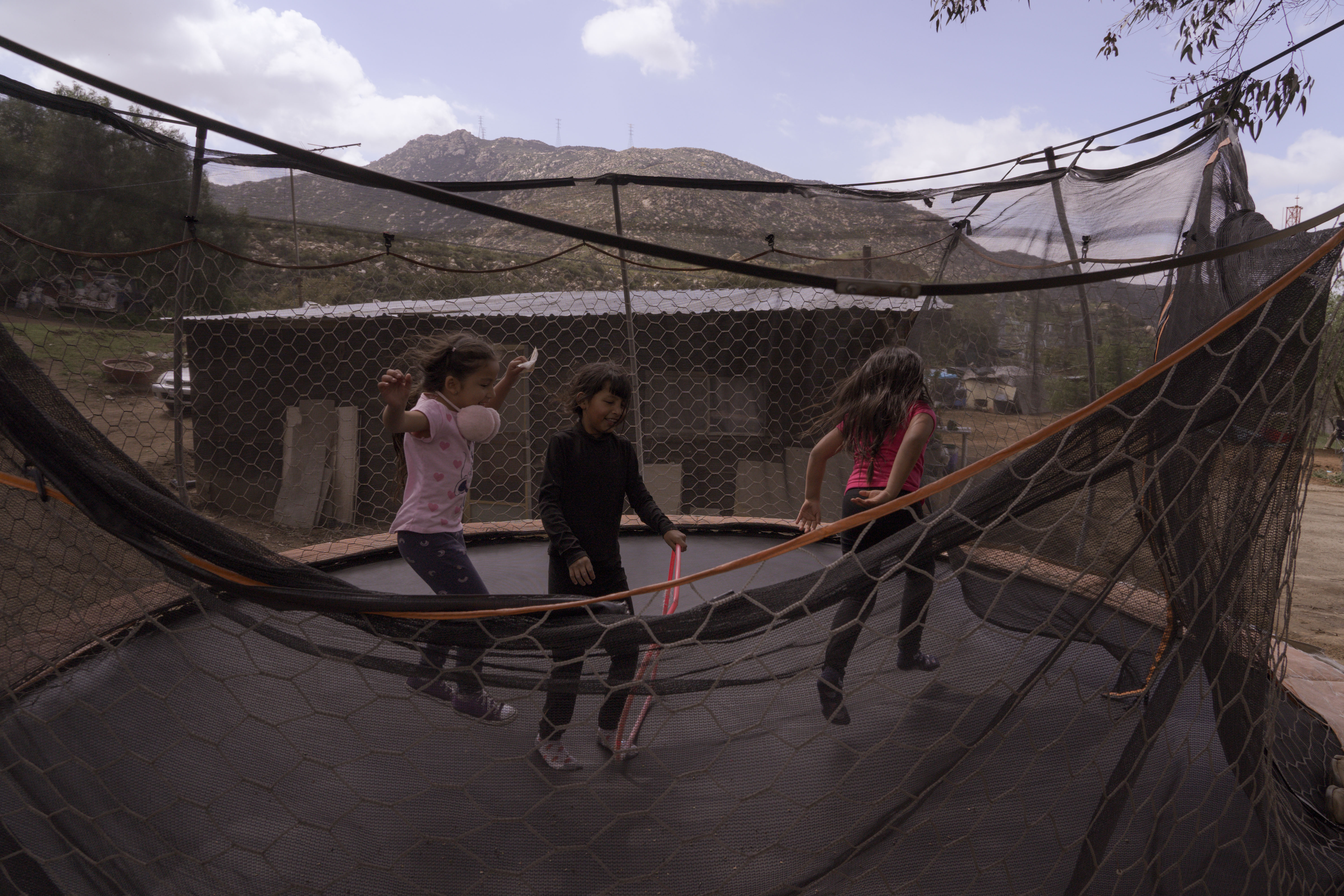 Bouncy outdoor trampoline with people jumping, situated in a mountainous landscape.