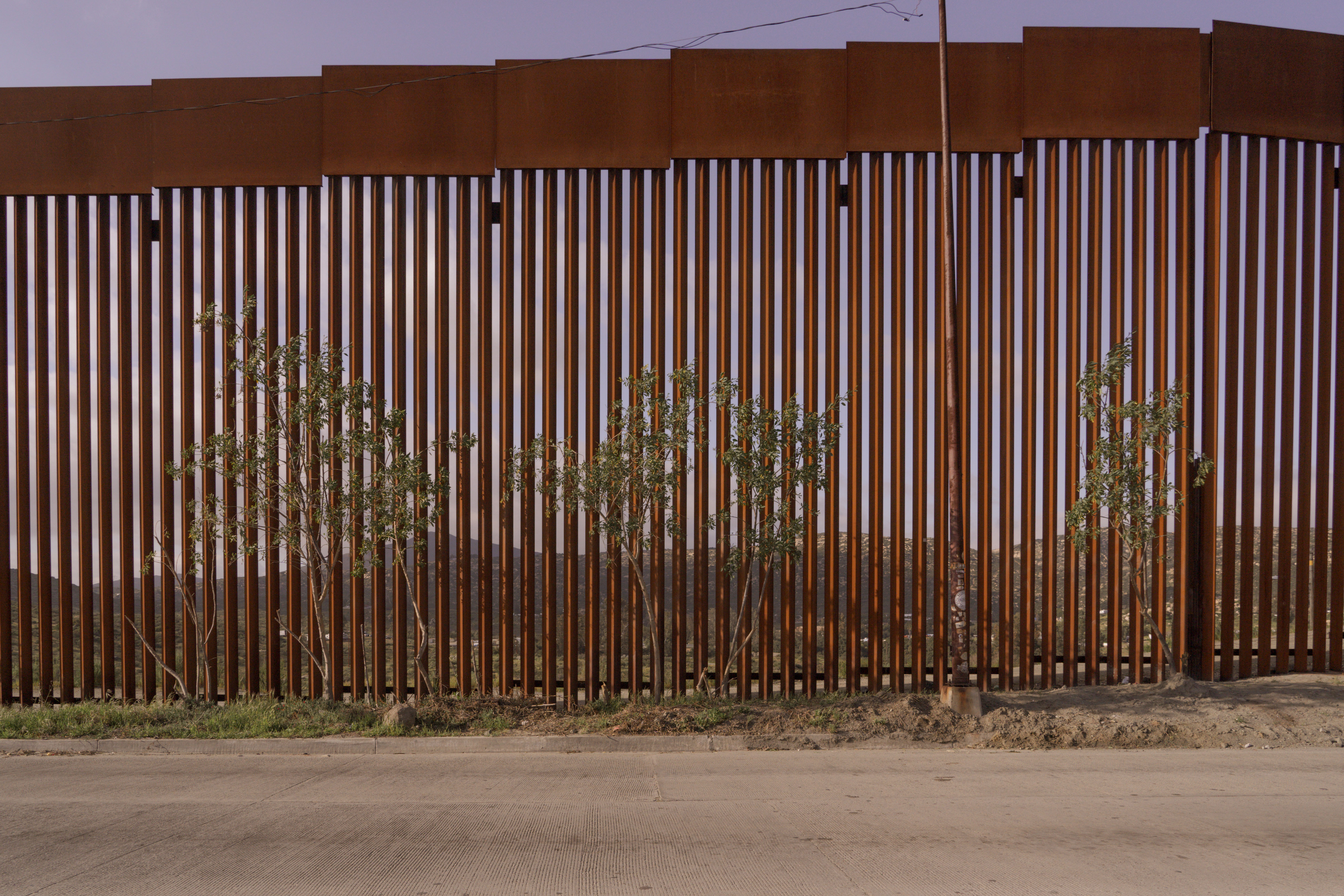 Tall brown metal fence panels against a desert landscape.