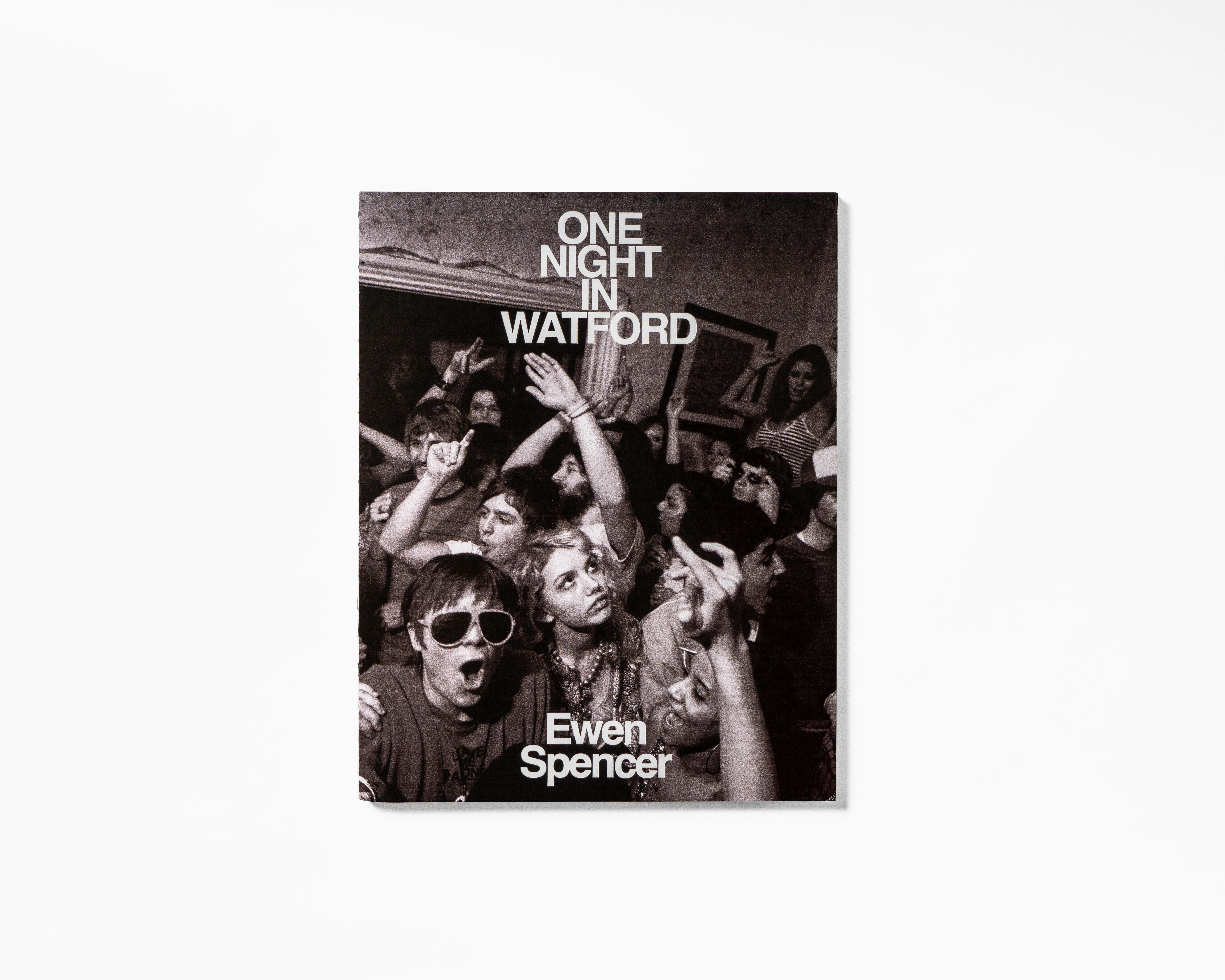 Book cover featuring black and white image of a crowd, with the title "One Night in Watford" and the author's name "Ewen Spencer".