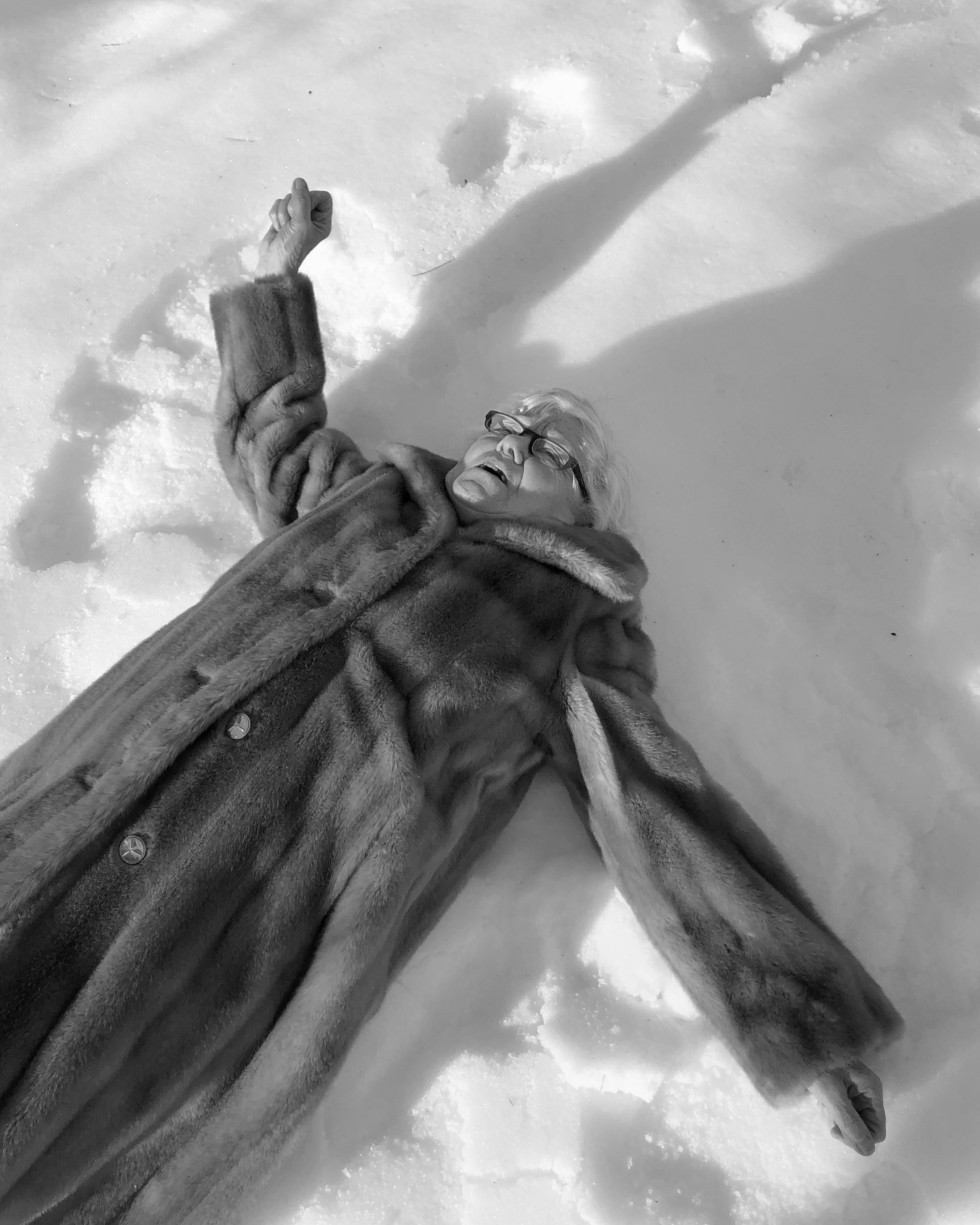 Stone statue of robed figure with raised fist viewed from below against cloudy sky, black and white photograph with dramatic upward angle.