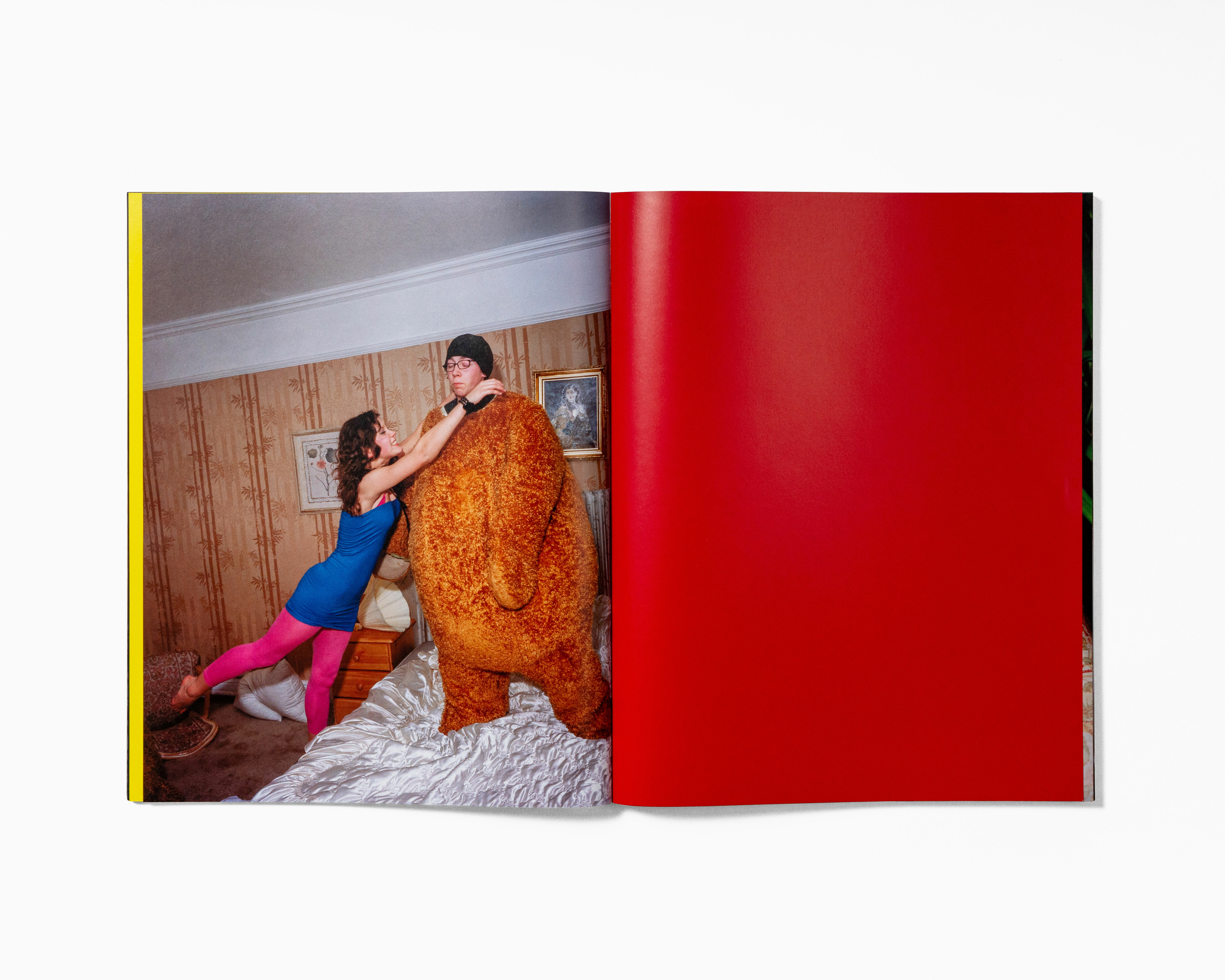 Two people embracing in an orange floral robe on a red background.