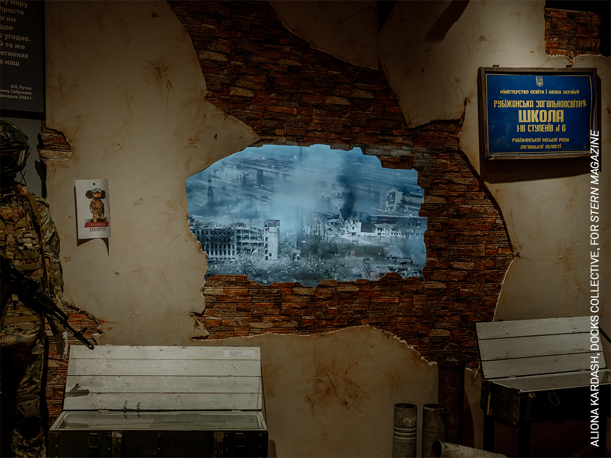 Aged brick wall with large framed image depicting a cityscape, bench in foreground.