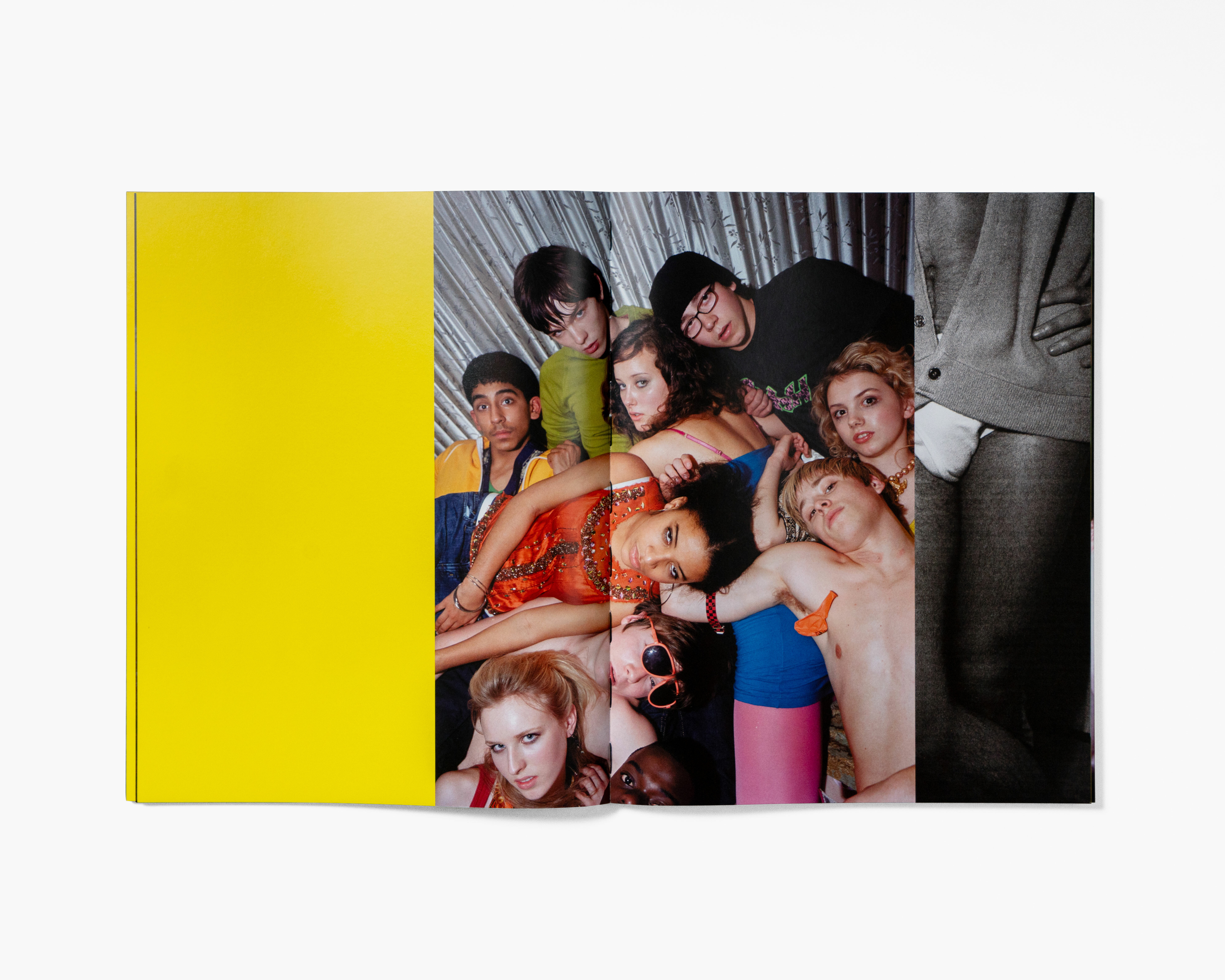 A group of young people gathered together, displaying a variety of colourful clothing and poses against a yellow backdrop.