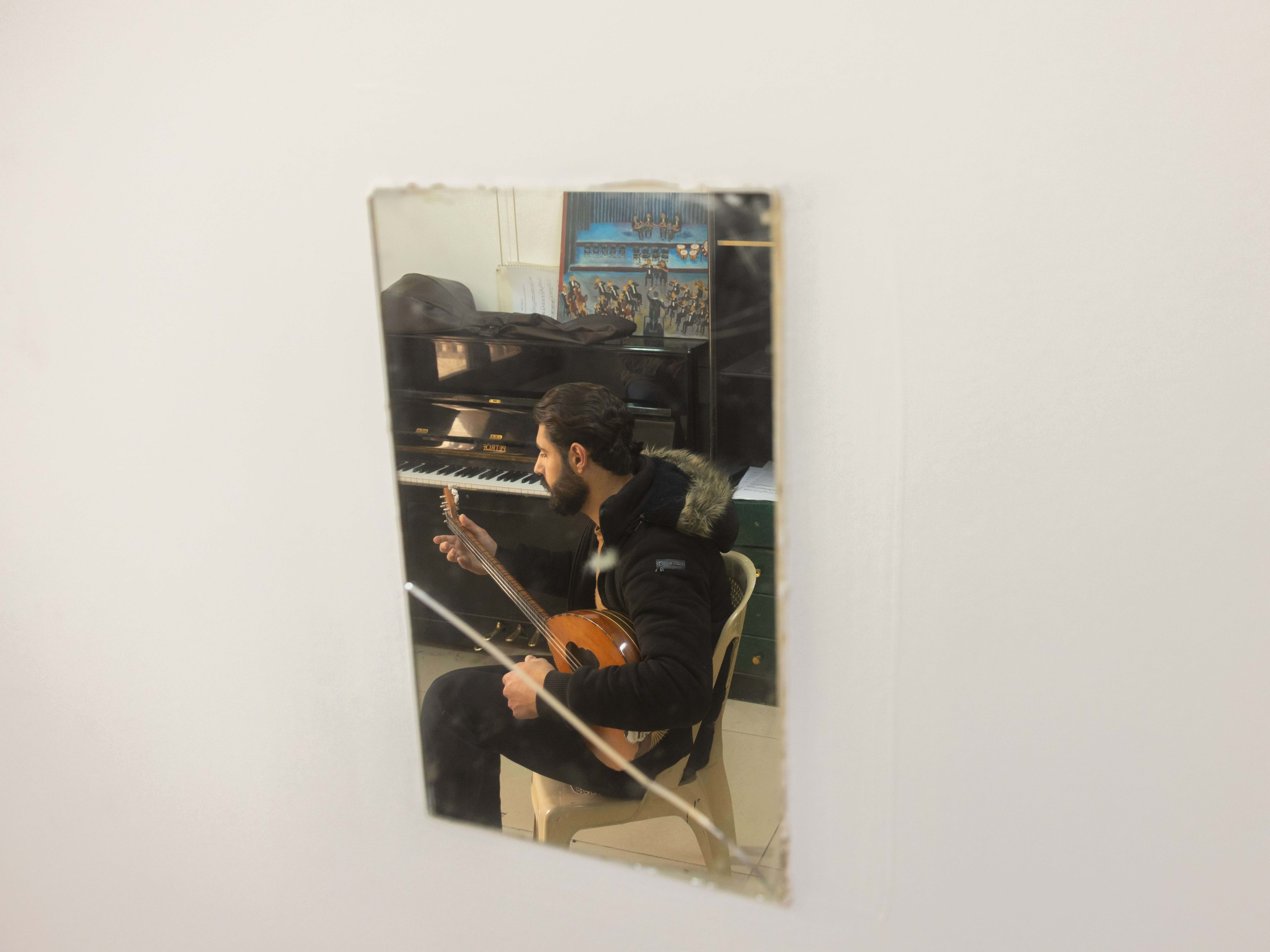 A man in a black outfit playing an acoustic guitar in front of an open equipment cabinet.