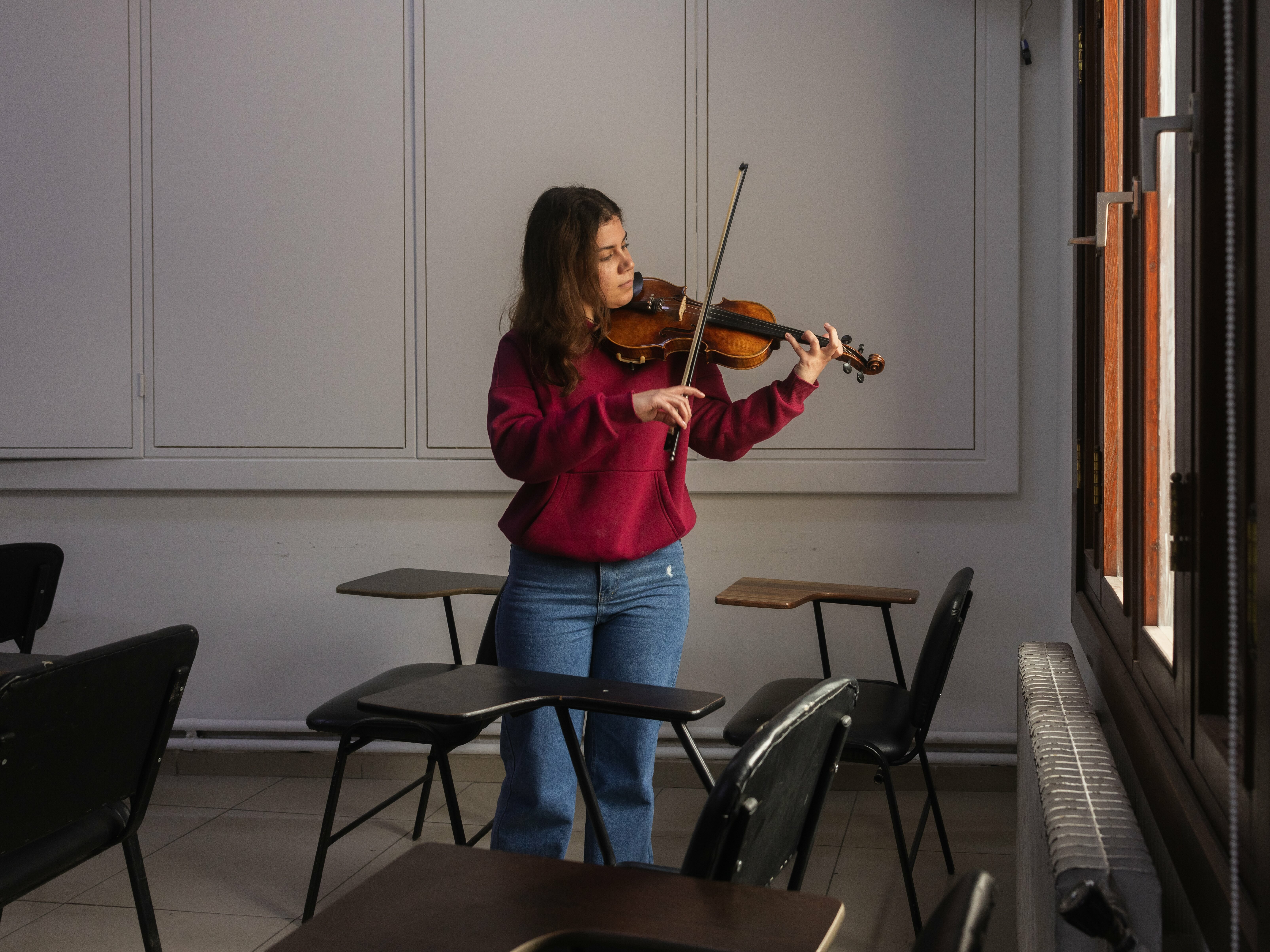 Young woman playing violin in classroom