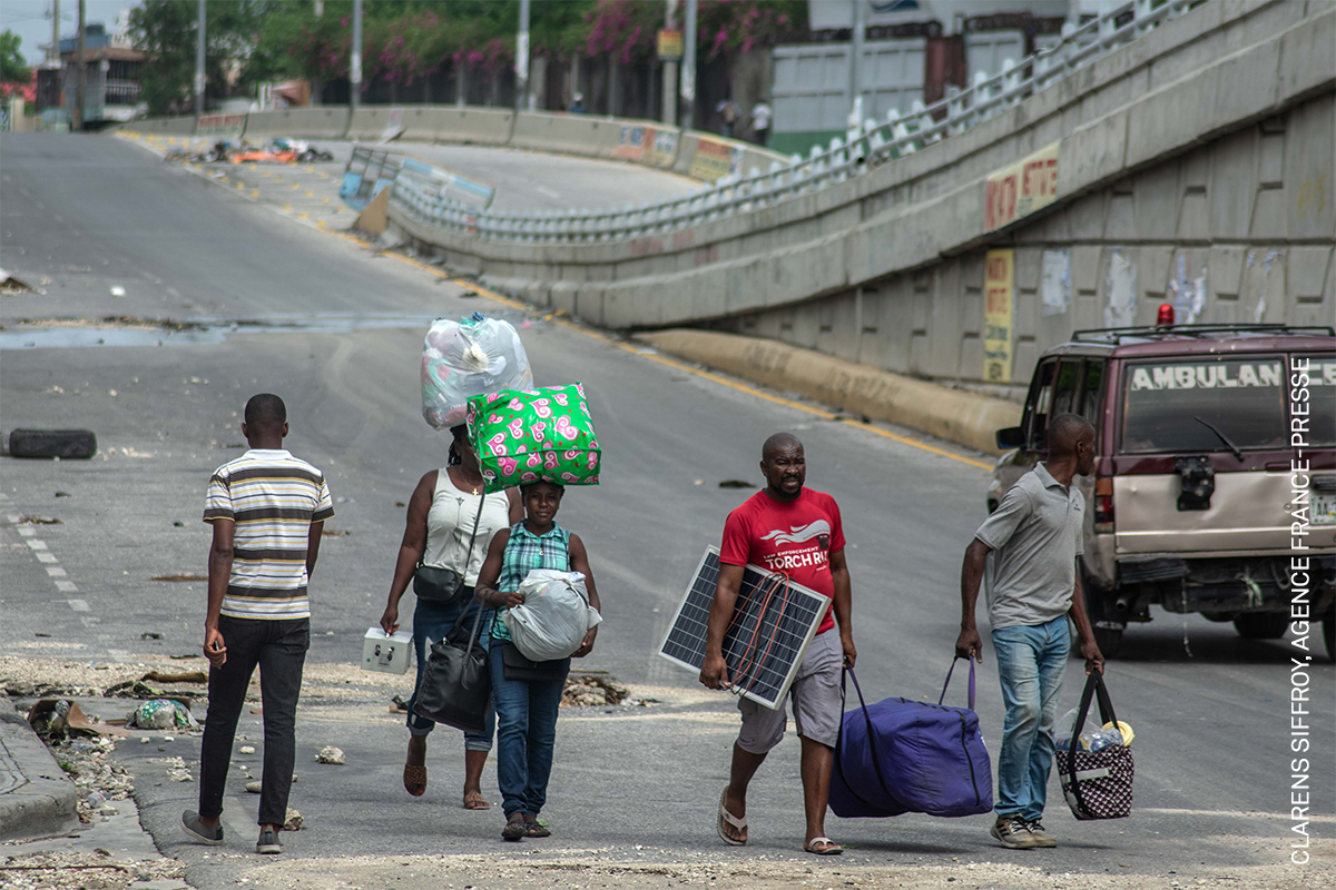 Diverse group of people walking in urban area, carrying bags and luggage.