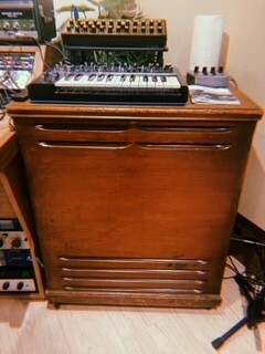Vintage wooden music console with multiple keyboards, buttons, and dials on a dark brown cabinet.