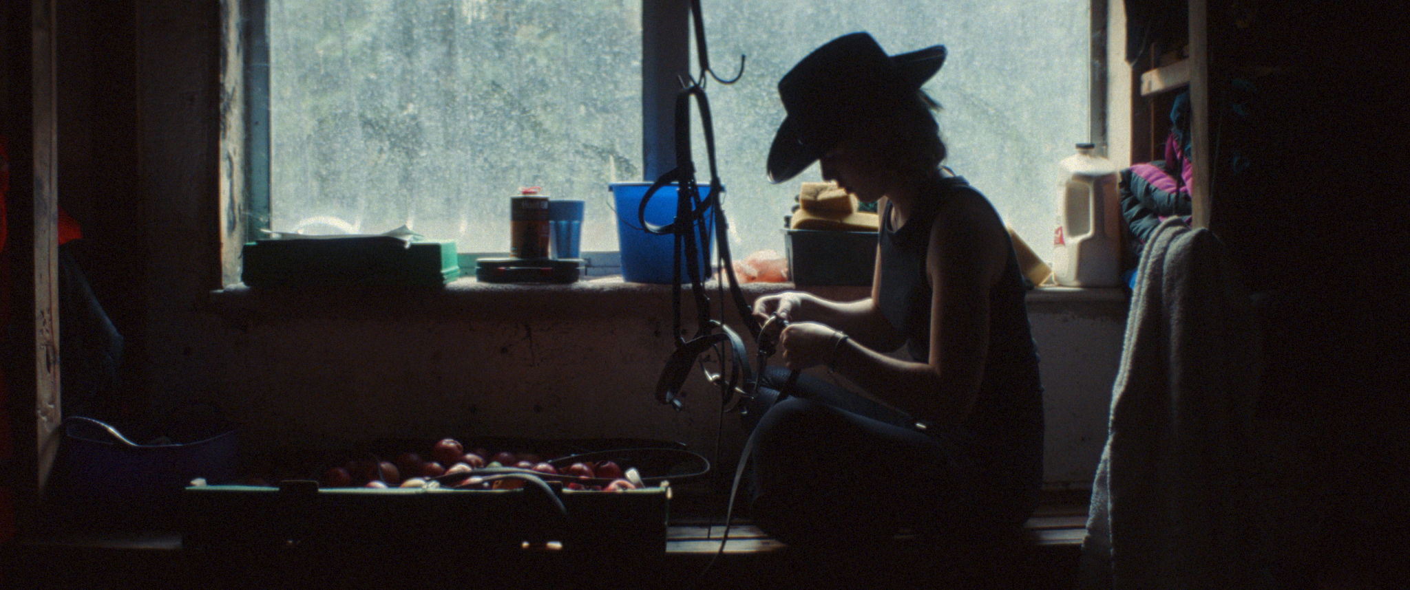 A silhouetted figure in a cowboy hat sitting at a piano against a dark background.