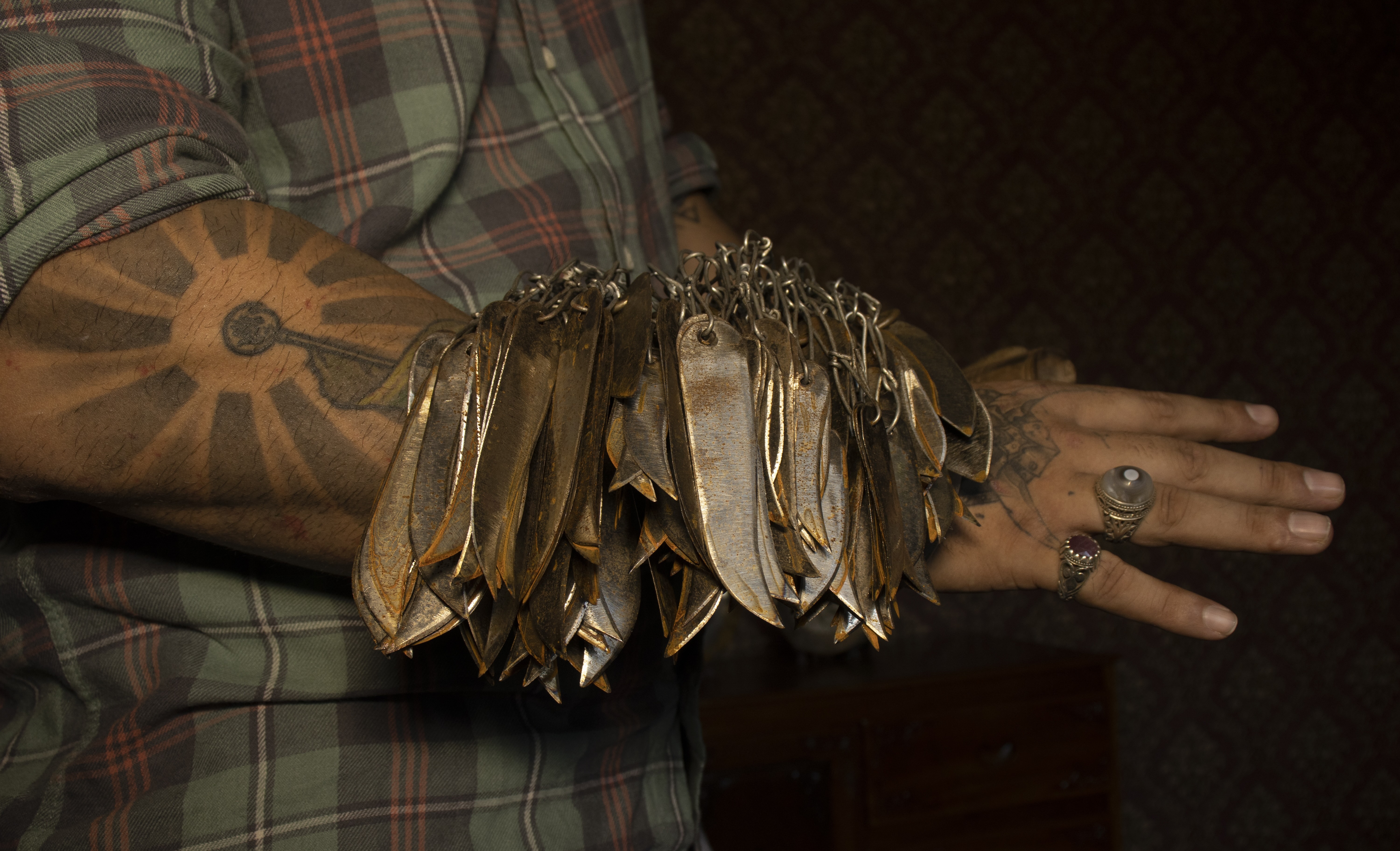 Worn tartan sleeve with hand holding a paper flower made from a brown, crumpled material.