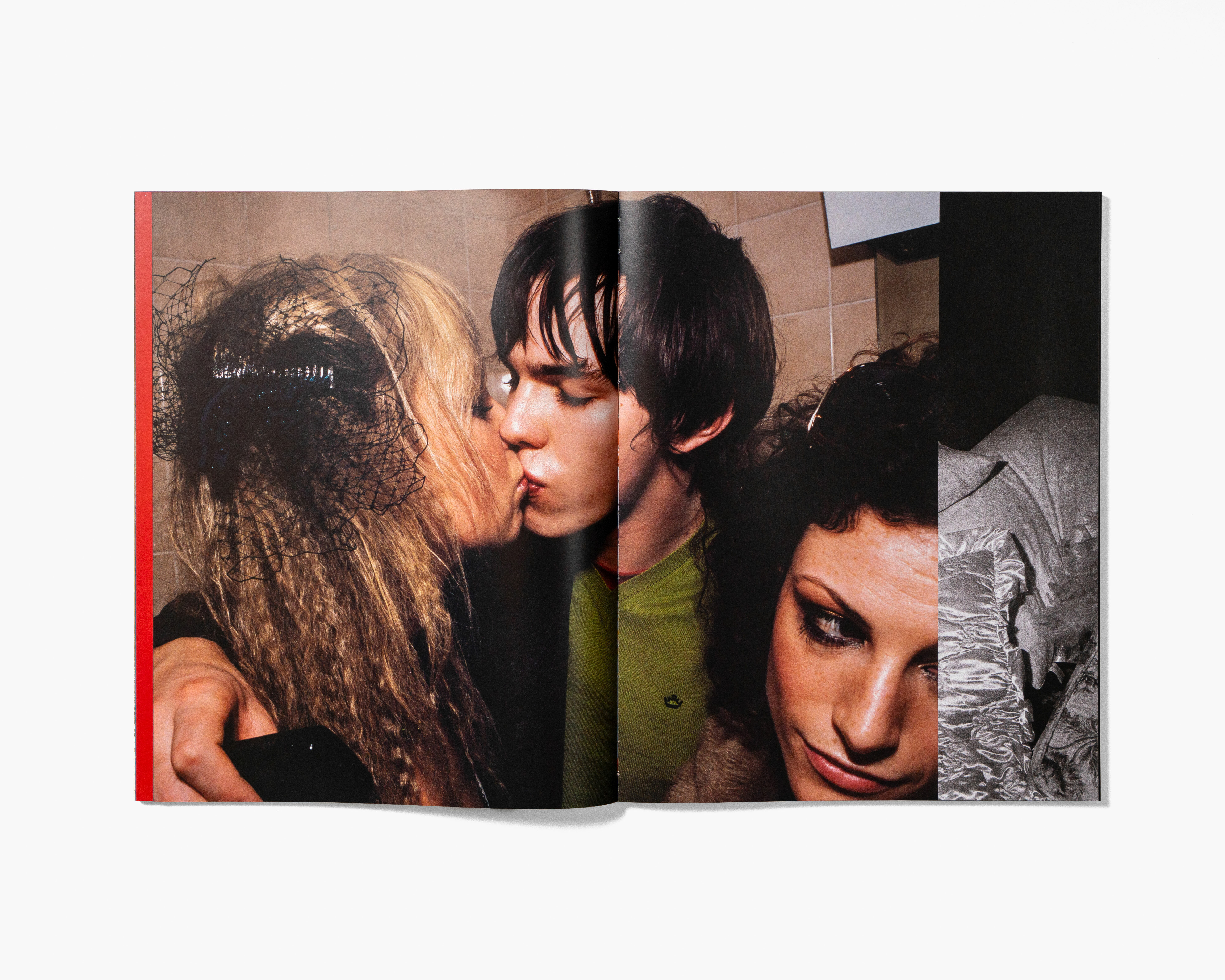 Three people closely embracing, with two individuals kissing. The image has a warm, intimate tone with a blur effect.