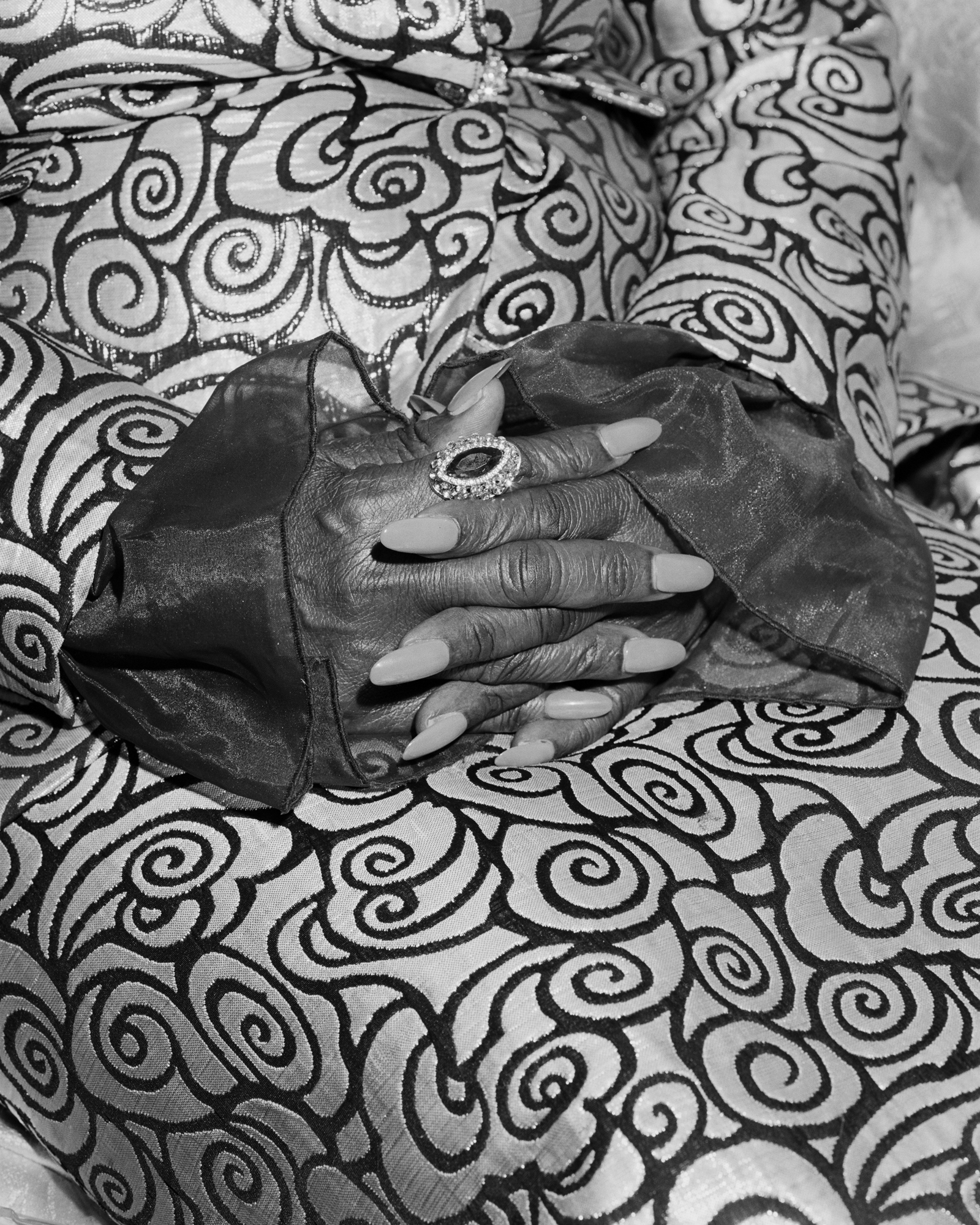 Wrinkled hands on ornate pattern