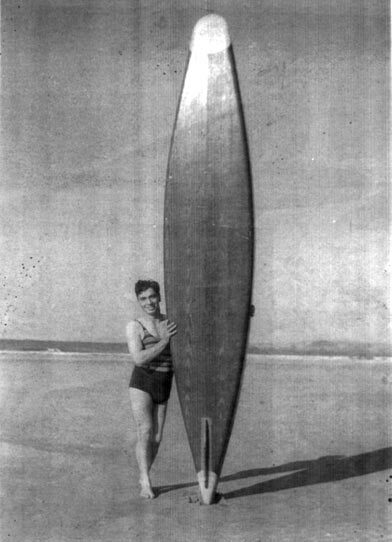 A person standing next to a large surfboard on a beach