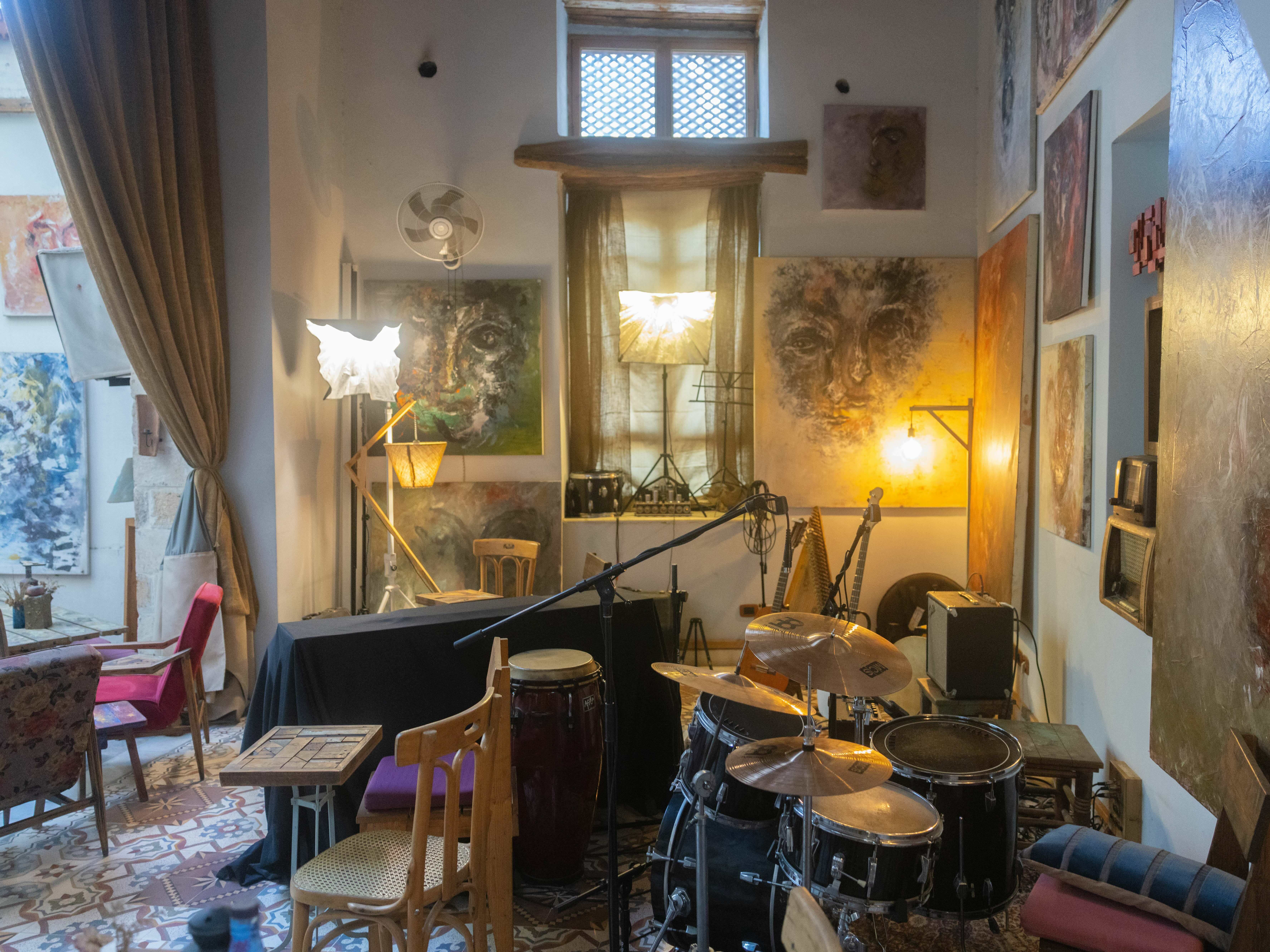 Cluttered interior with musical instruments, lamps, and art on the walls, creating a cosy, eclectic atmosphere.