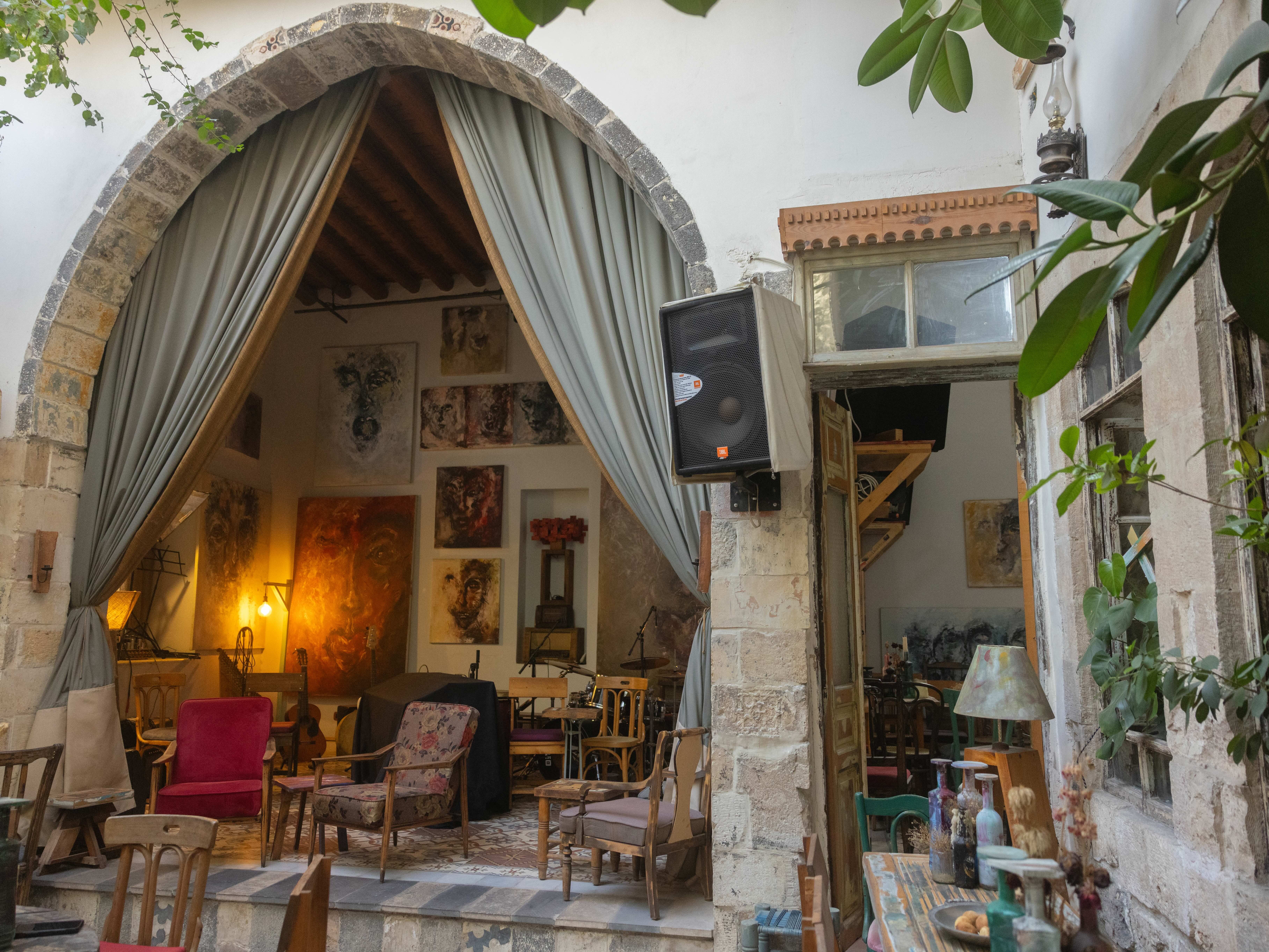 Arched doorway leads to cosy indoor space; stone walls, curtains, vintage furniture and decor.