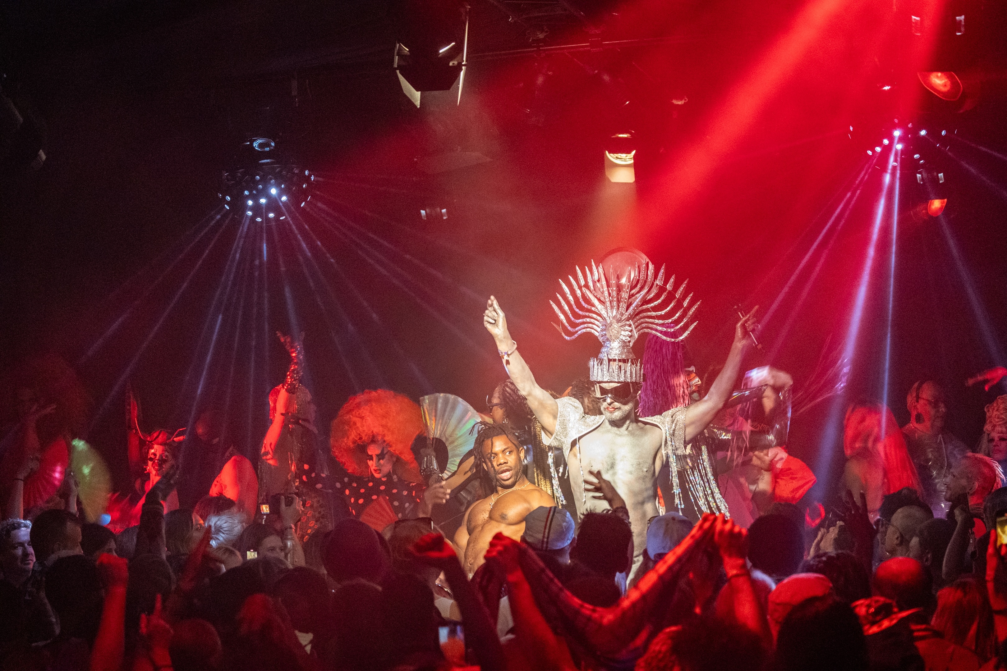 Elaborate theatrical performance on stage with dancers in red costumes and dramatic lighting.