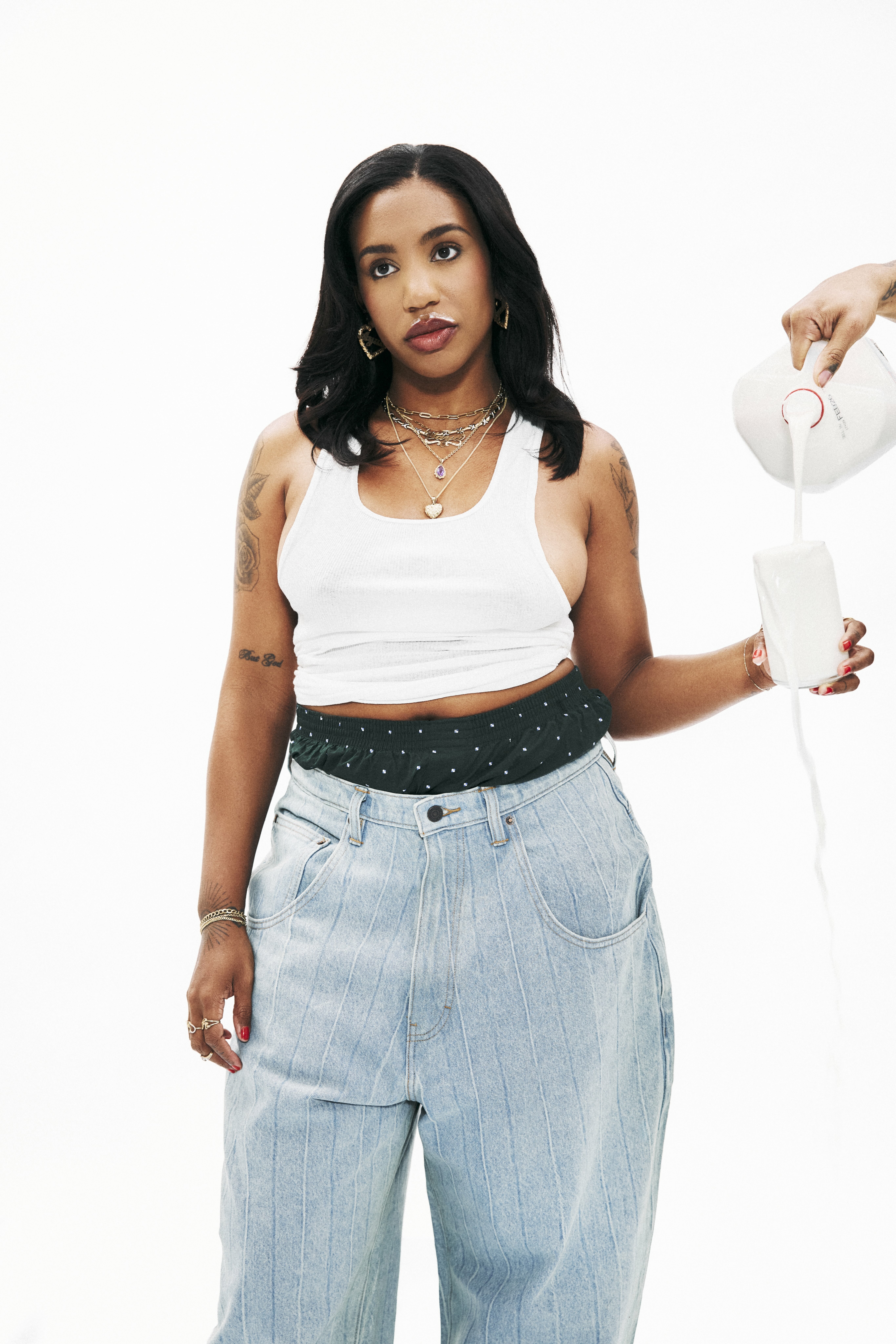 Woman wearing white top, green patterned belt, and light blue jeans.