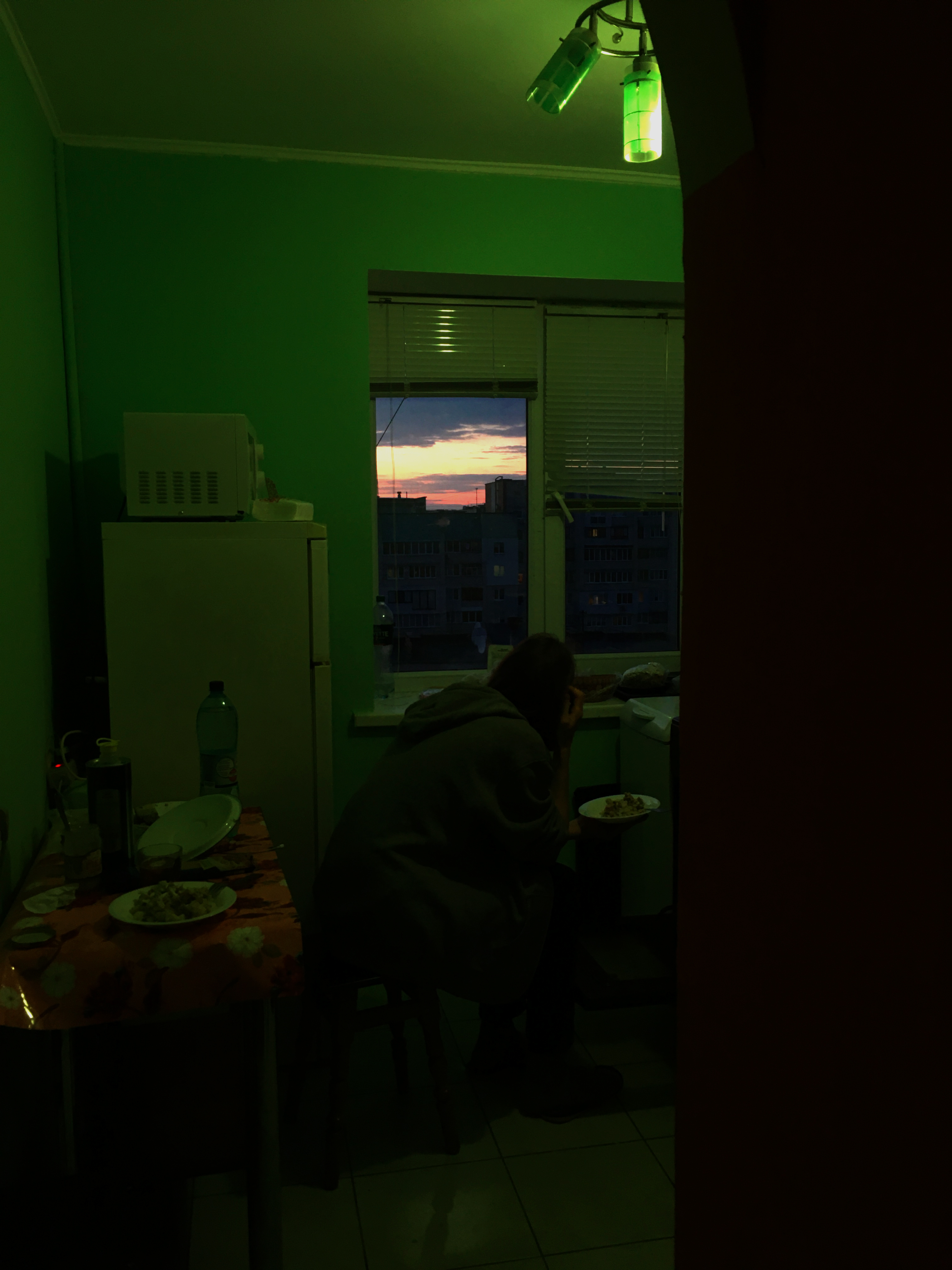 Dark room with a window revealing a sunset view of the sky in the distance.