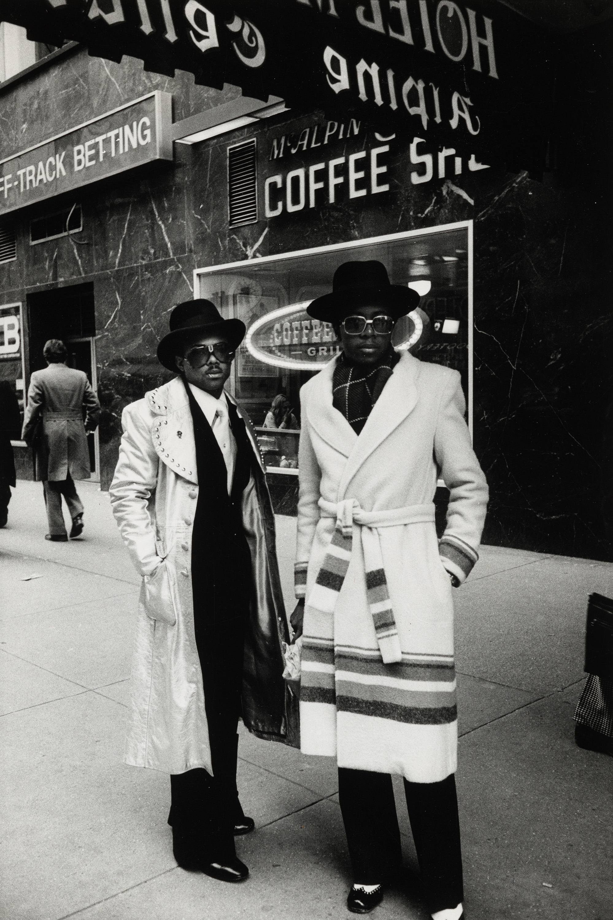 Two men in winter coats and hats standing in front of a coffee shop.