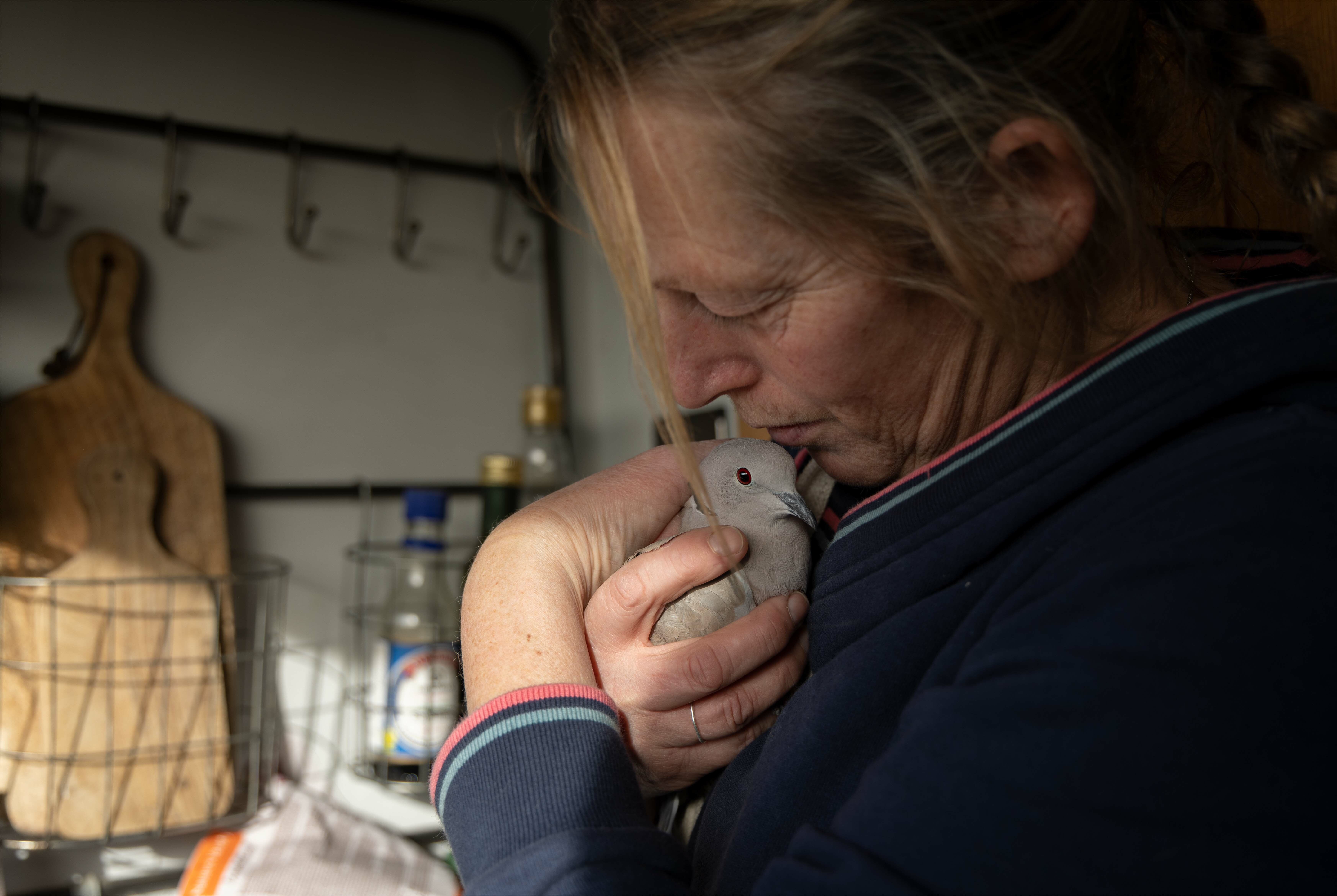 A woman holding a small white pet rodent in her hand, looking down at it tenderly.