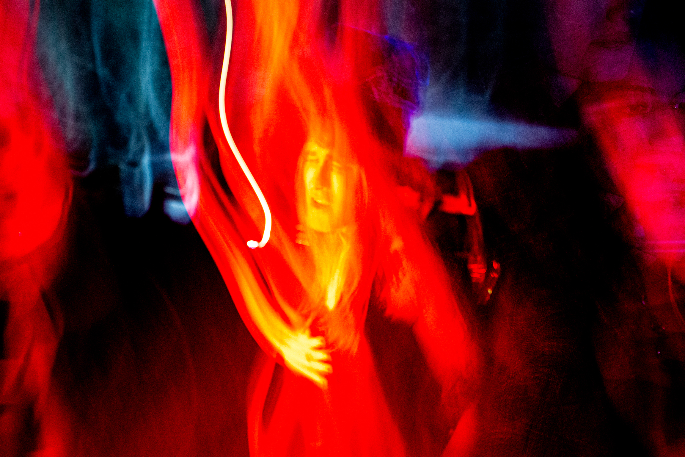 Abstract composition with vibrant red and orange streaks, white curved lines, purple accents, and dark silhouettes against blurred background.