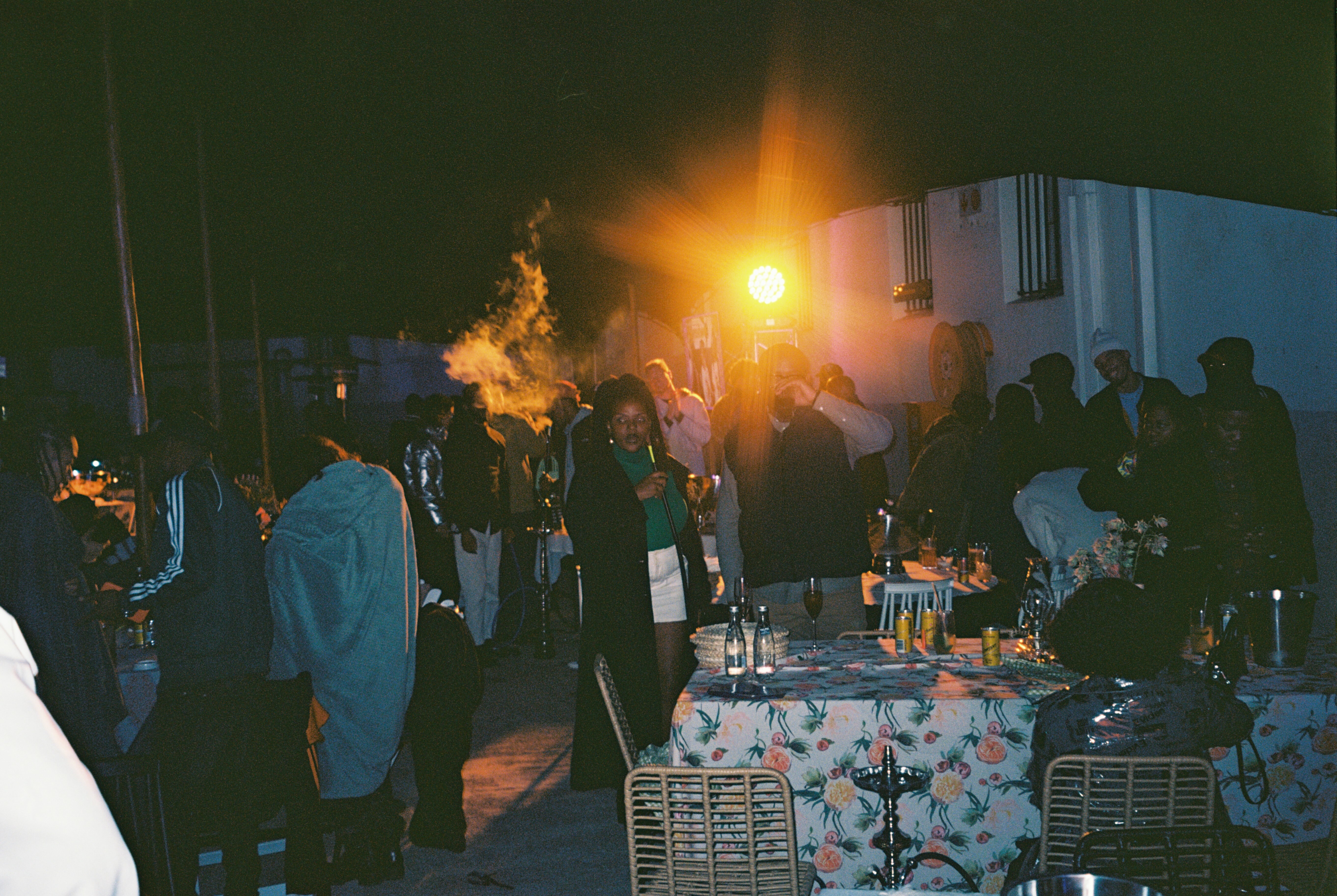 Crowd gathered around outdoor fire on night, silhouetted figures, flaming objects visible.