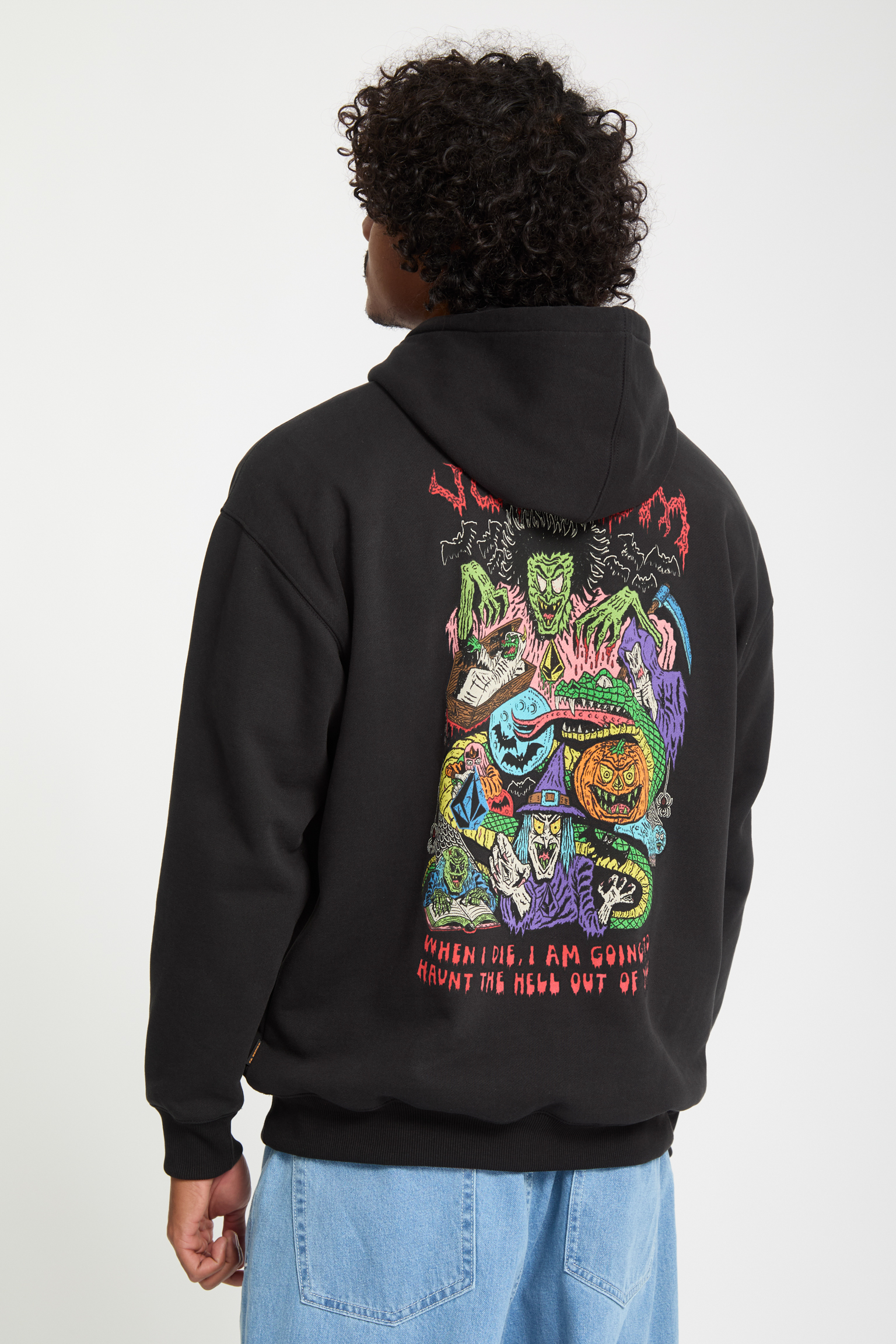 Person wearing dark grey hoodie with colourful monster graphic on back, featuring green, purple, blue, and red creatures with text below.