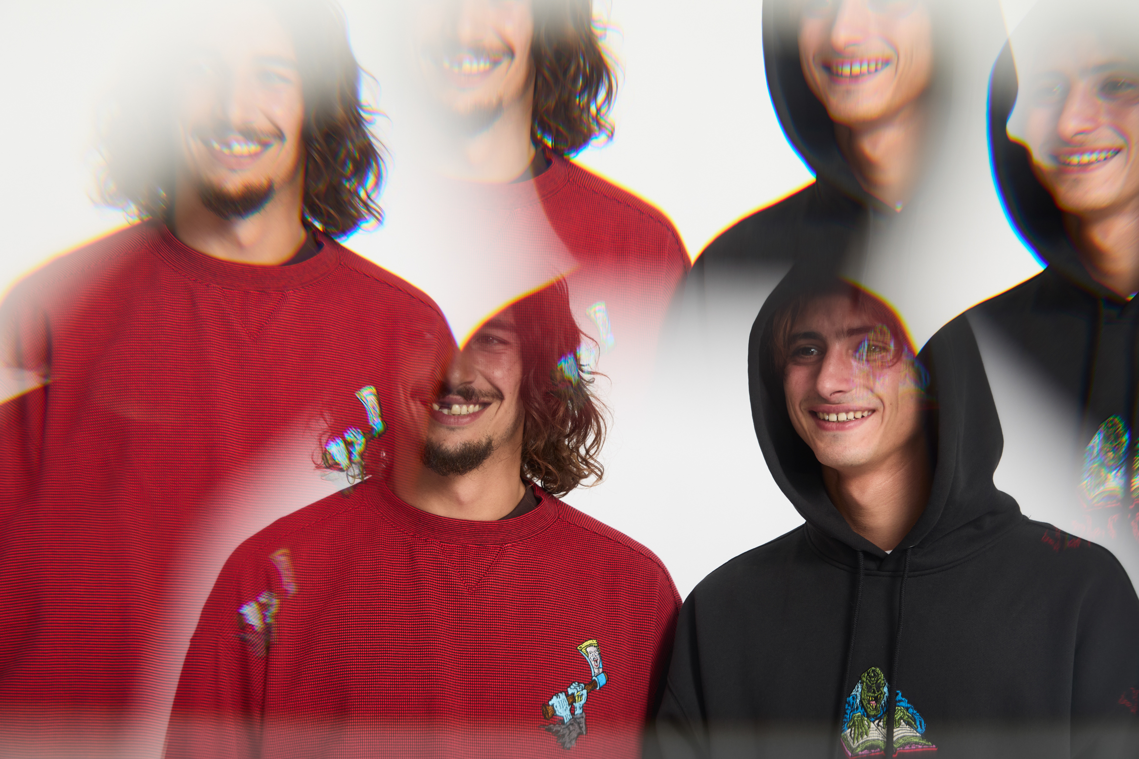 Multiple overlapping exposures of two people in red and black hoodies with cartoon graphics, creating blurred motion effect.
